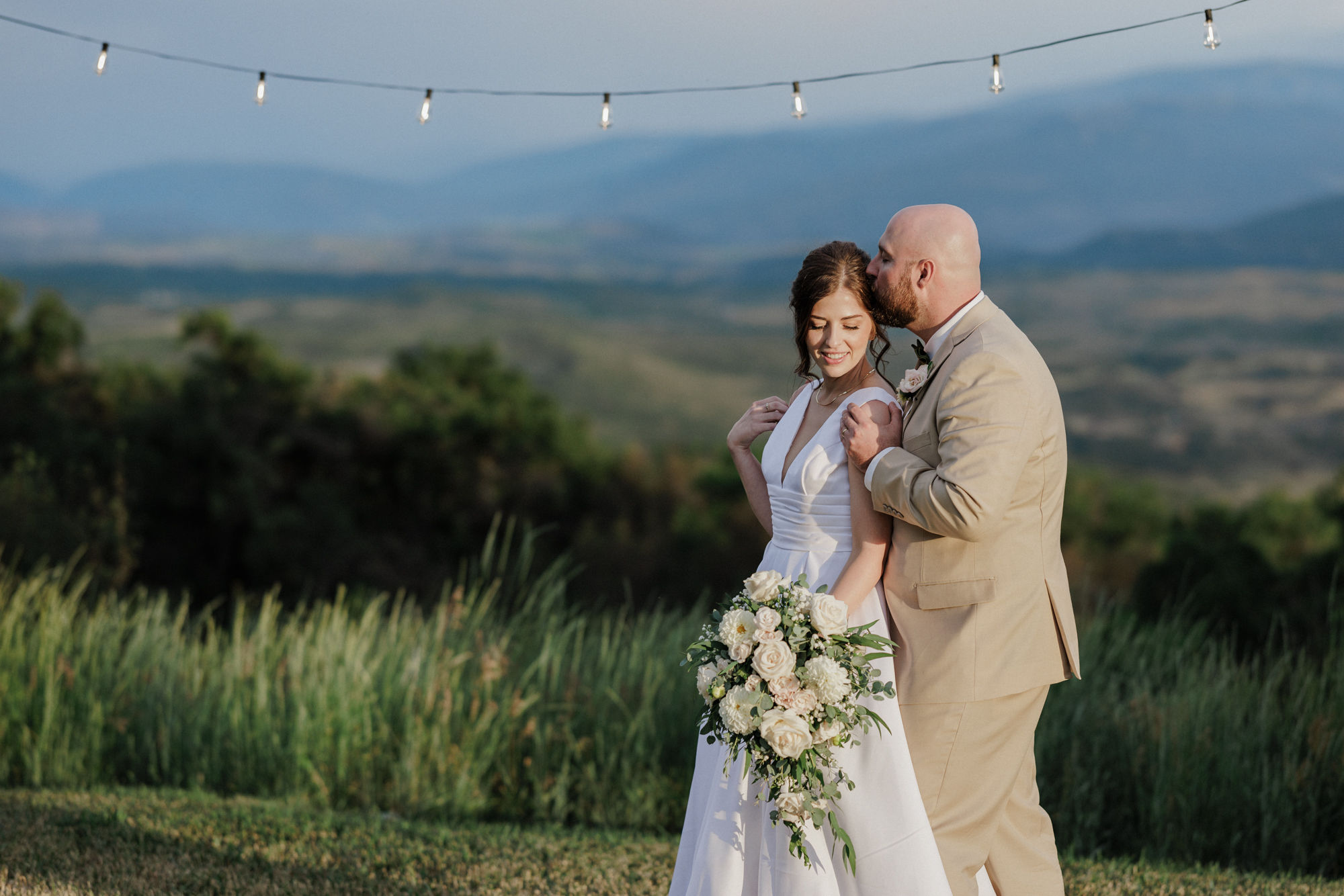 bride and groom stand in yard of colorado airbnb during sunset photos