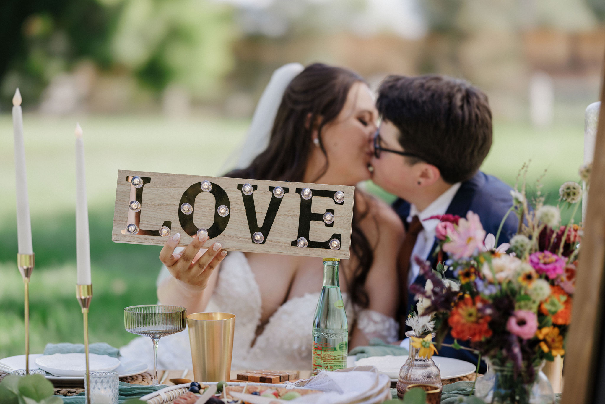 brides kiss and hold up love sign