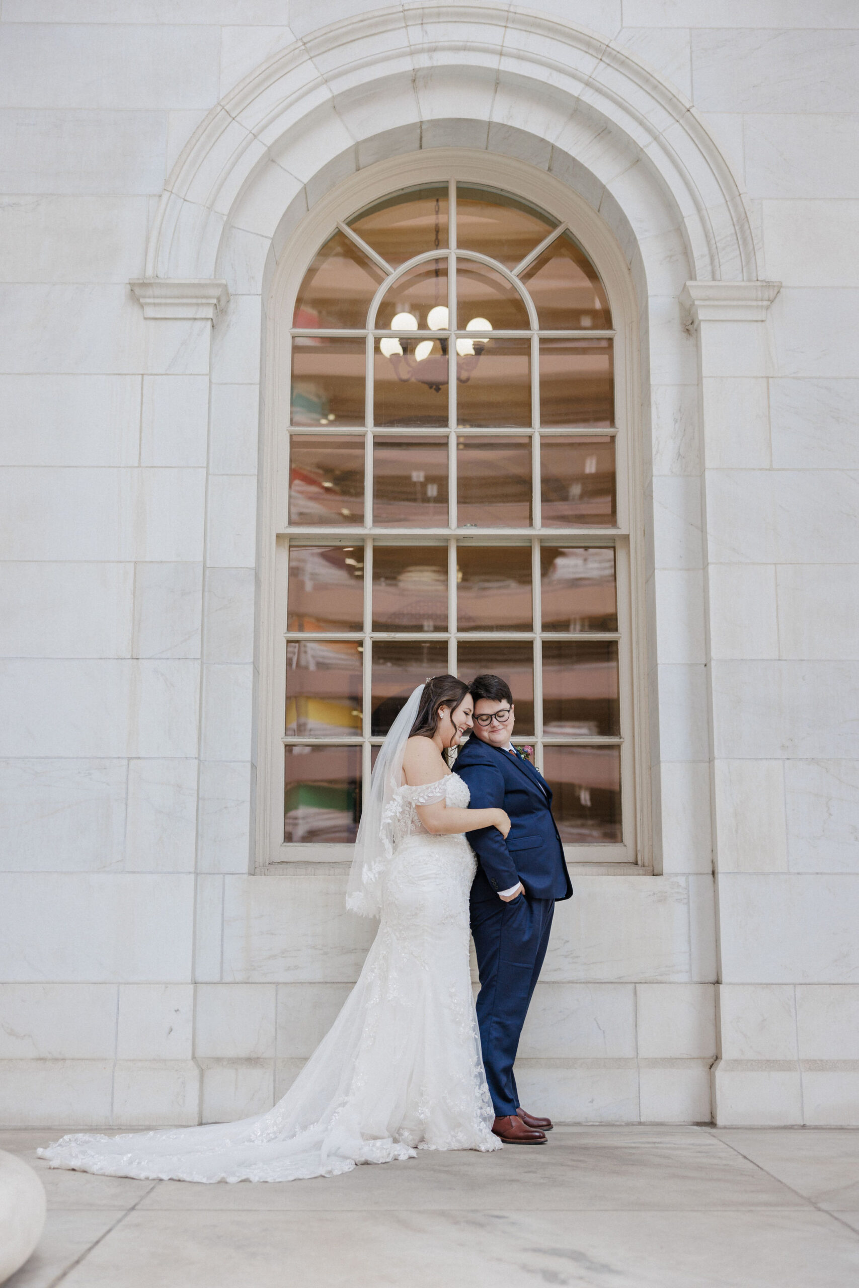 lgbtq+ couple embraces in front of gold window at byron white courthouse in denver