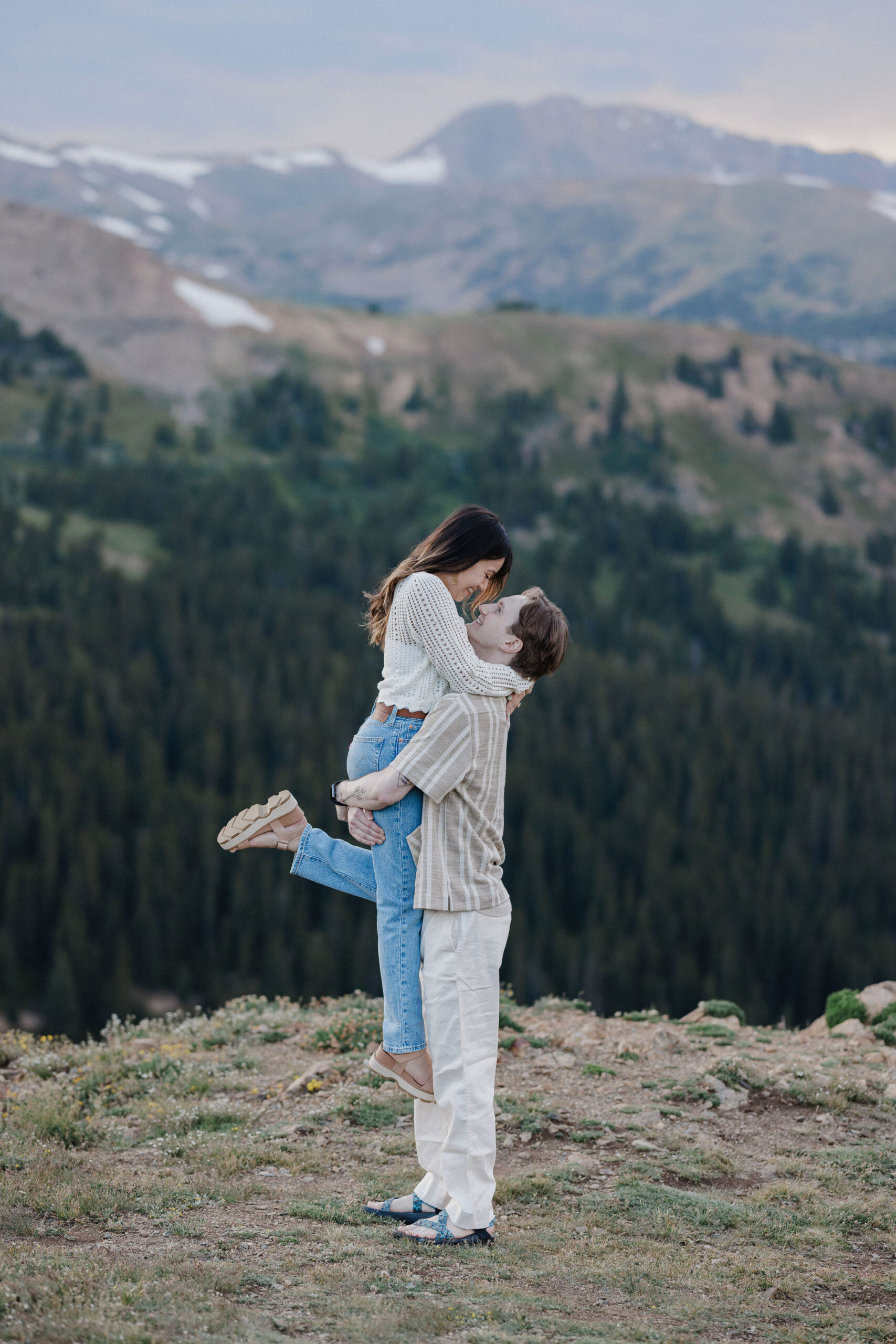 man lifts woman up in the breckenridge colorado mountains during engagement photos