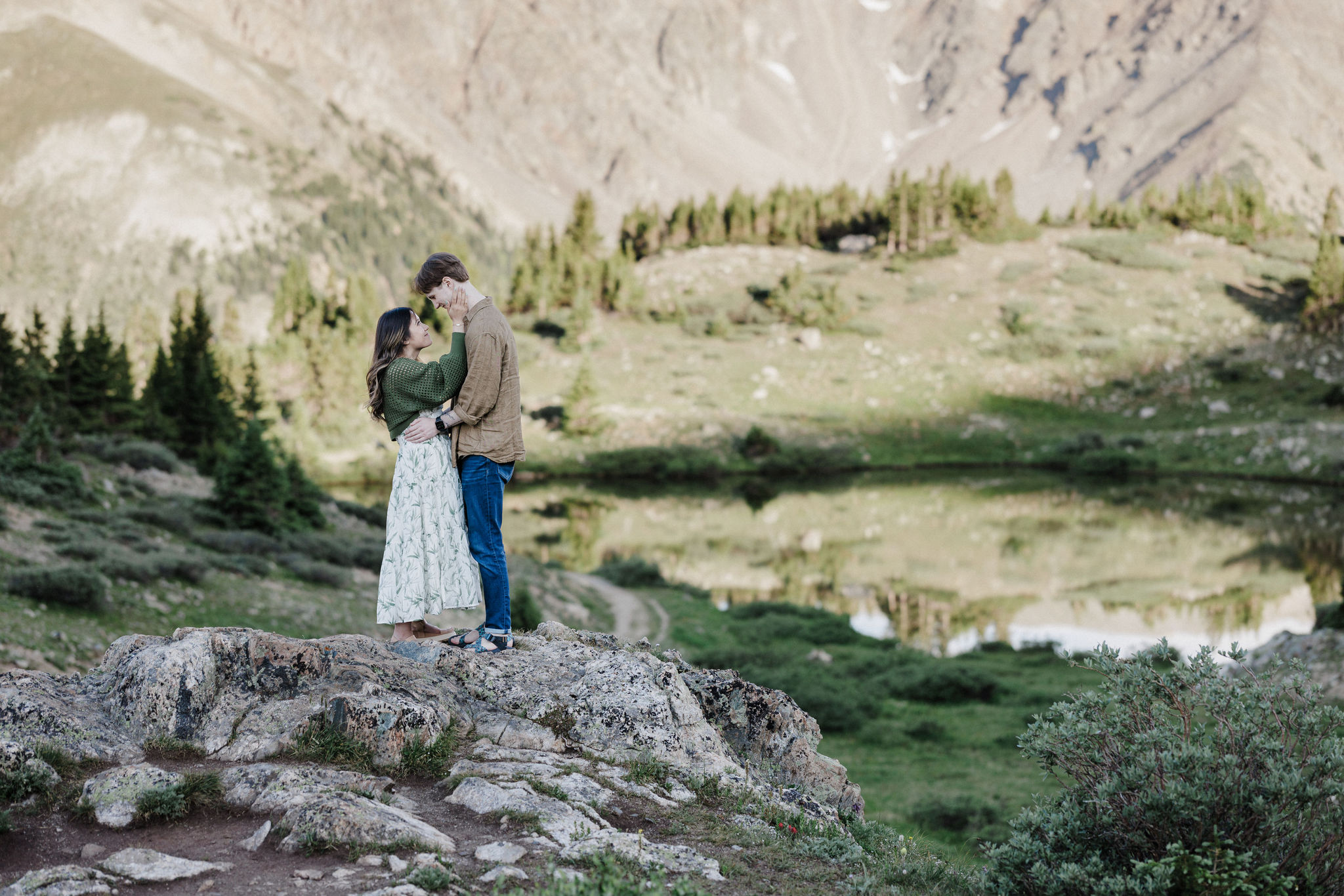 engaged couple stands on rock and embrace each other during breckenridge engagement photo shoot