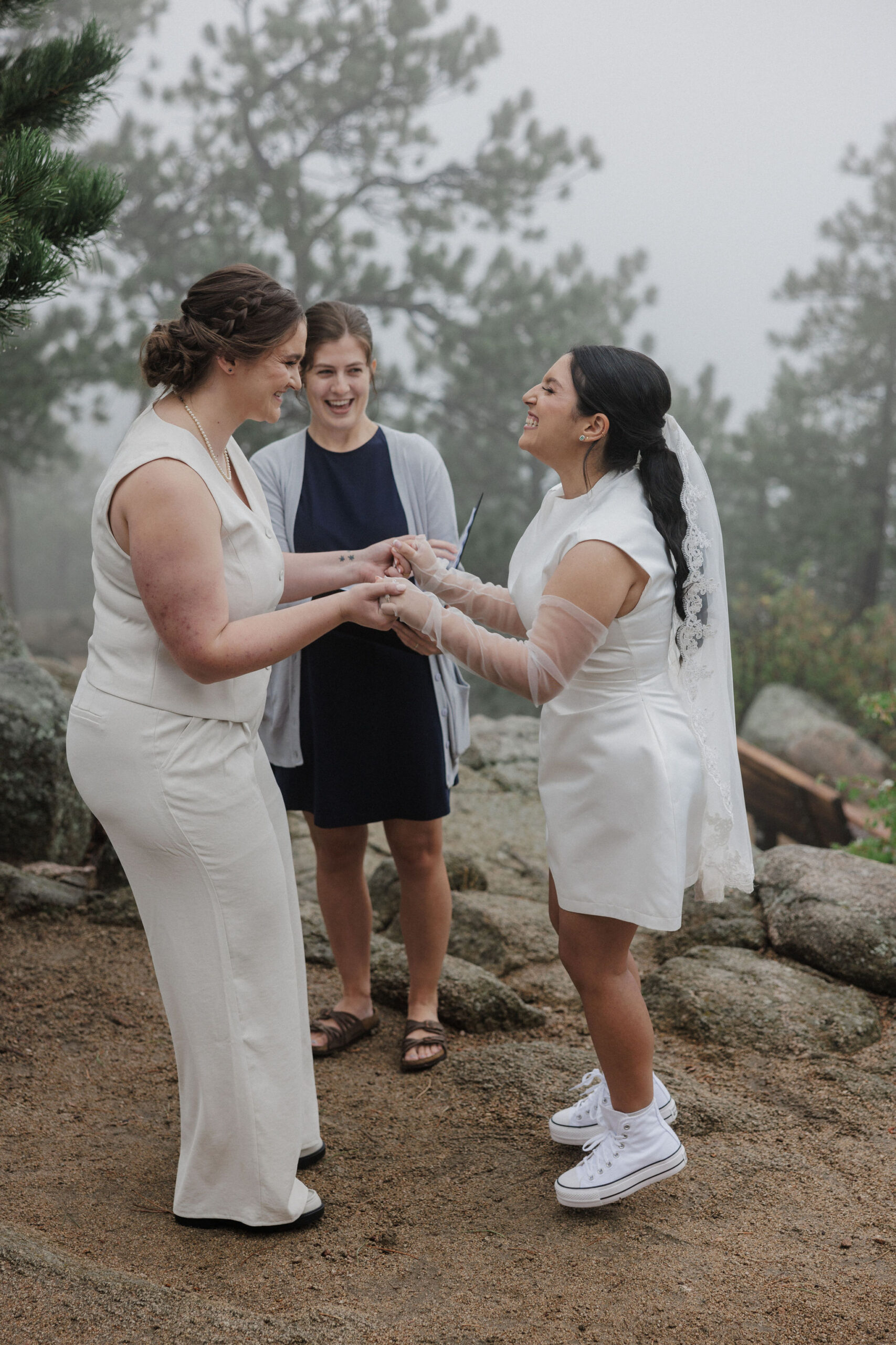 two brides hold hands and jump after elopement ceremony in boulder colorado