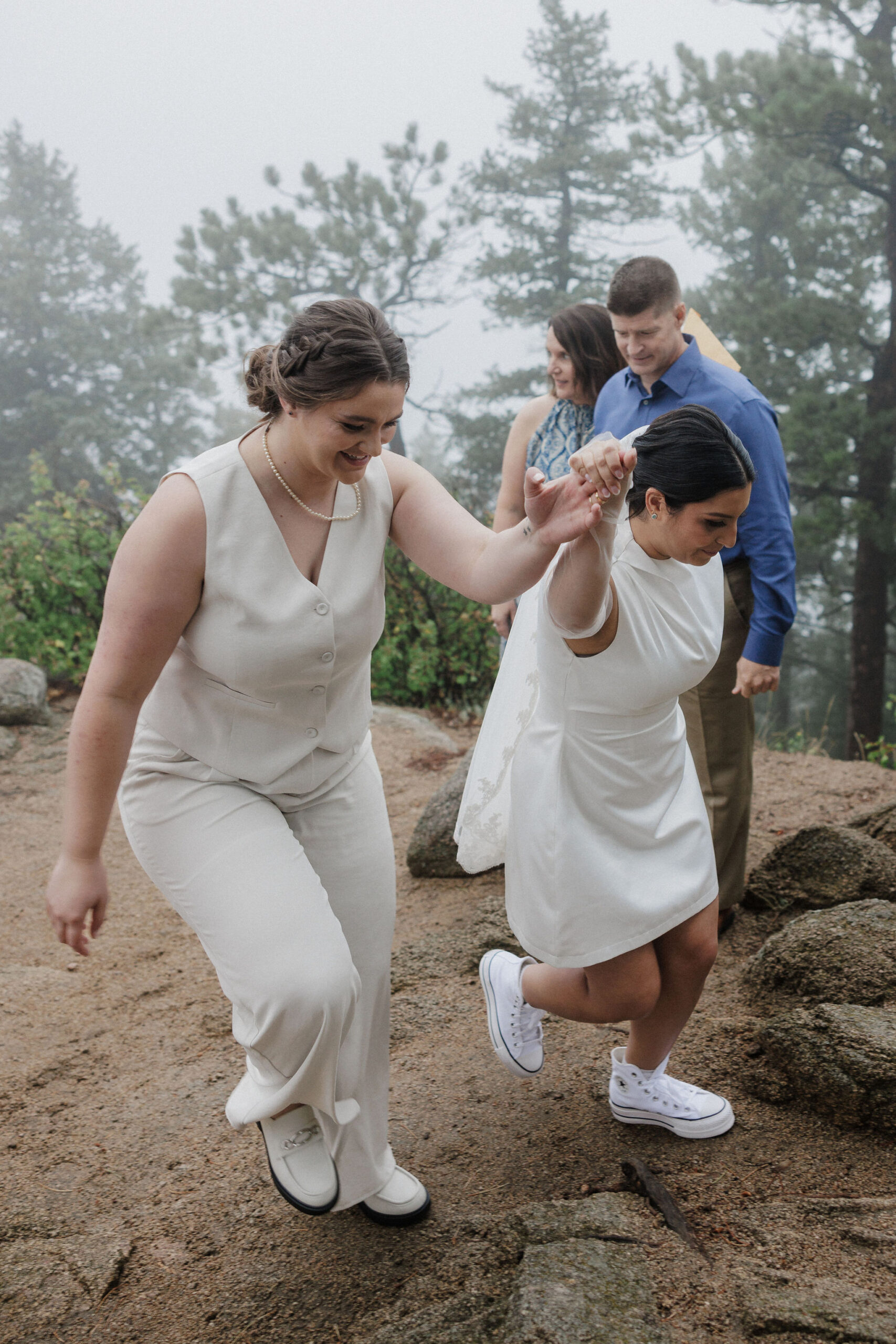 brides walk hand in hand up a trail during boulder colorado elopement ceremony