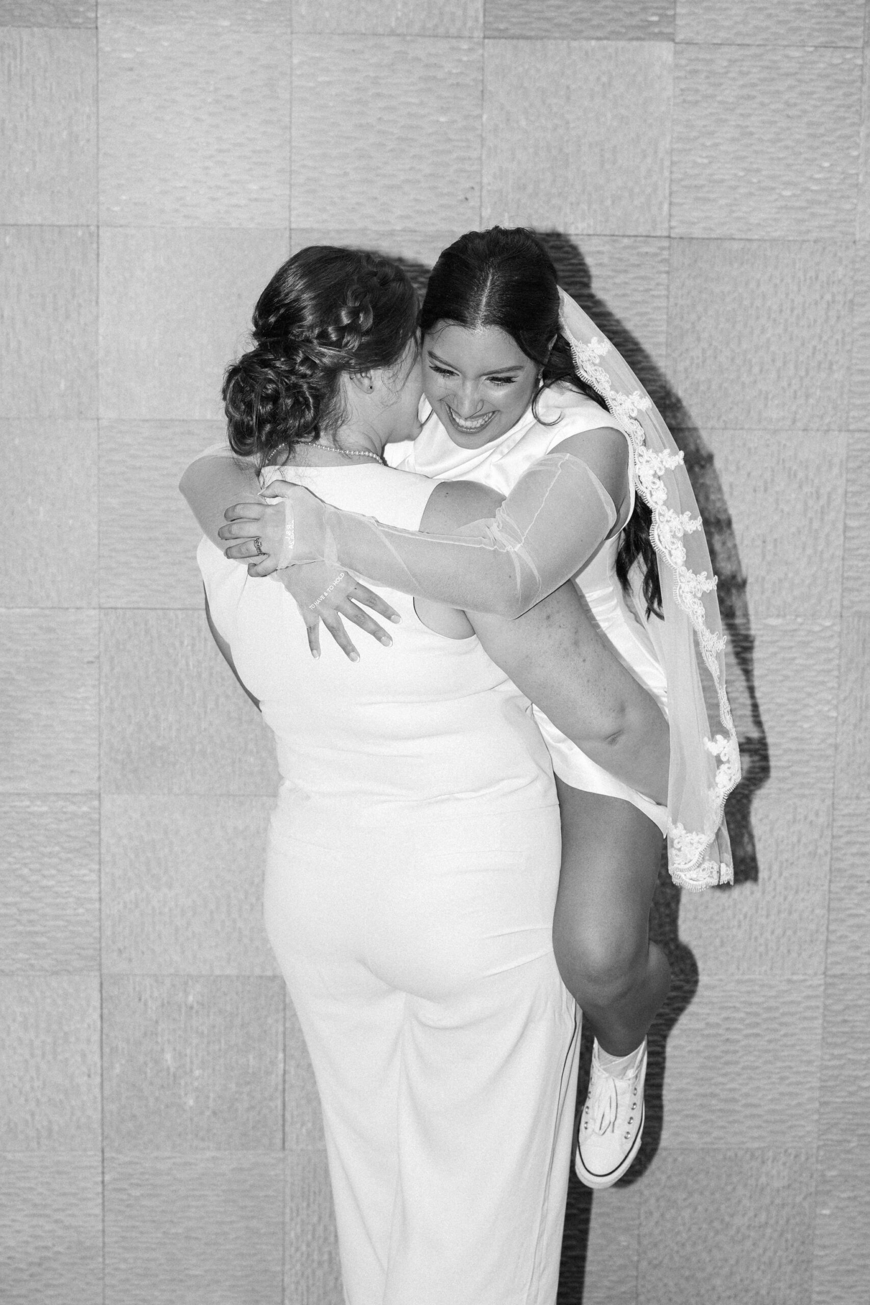 bride lifts bride up during elopement photos in boulder hotel