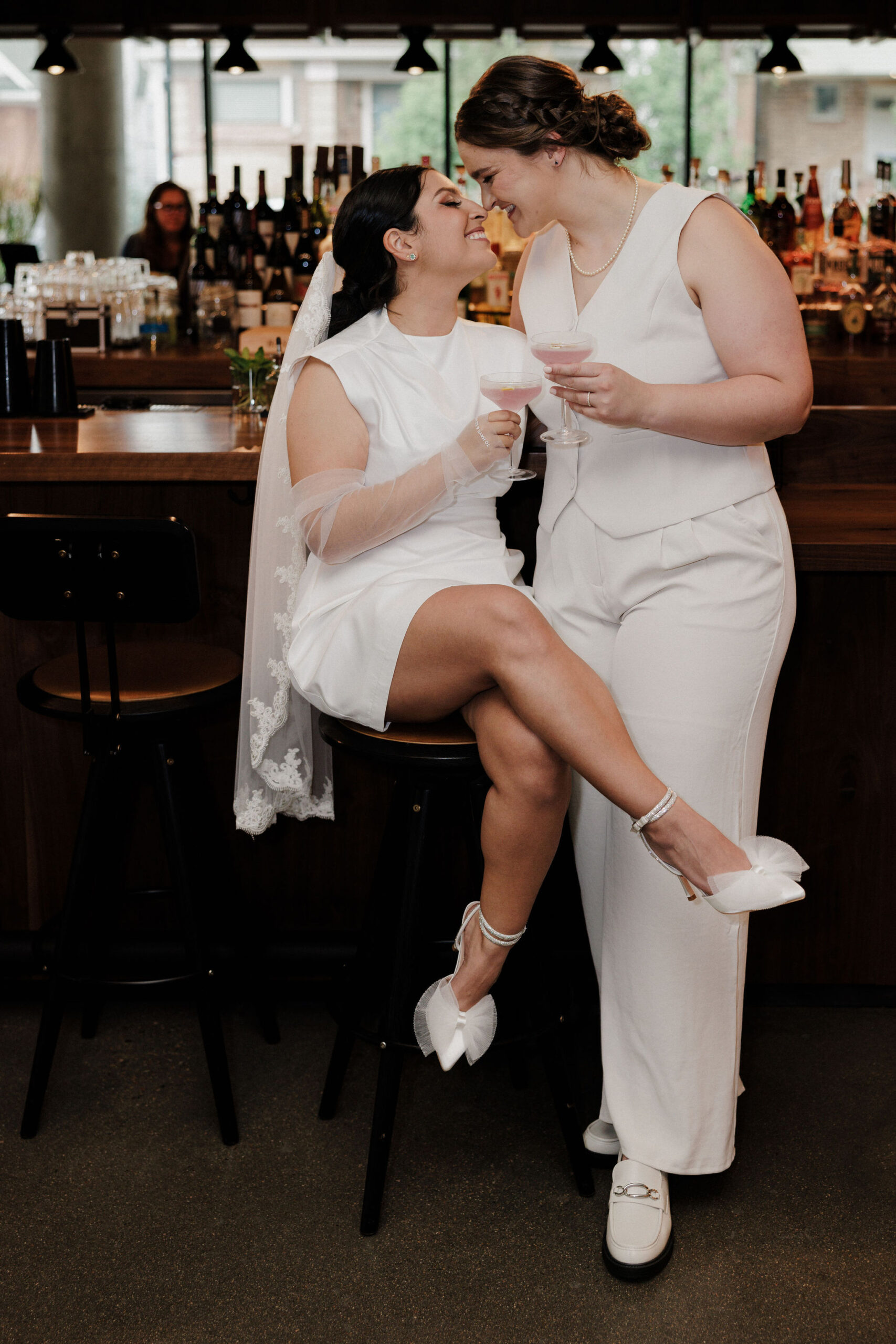 two brides go in for a kiss while at the hotel bar during boulder elopement