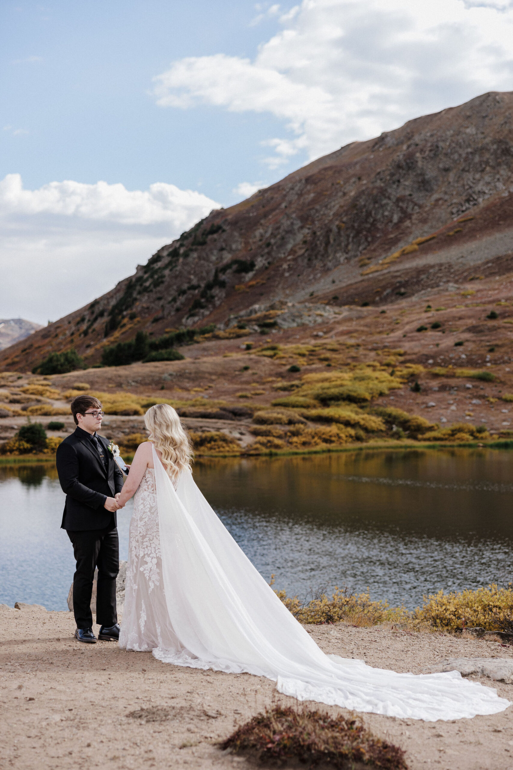 bride and groom stand at loveland pass lake during private vow reading