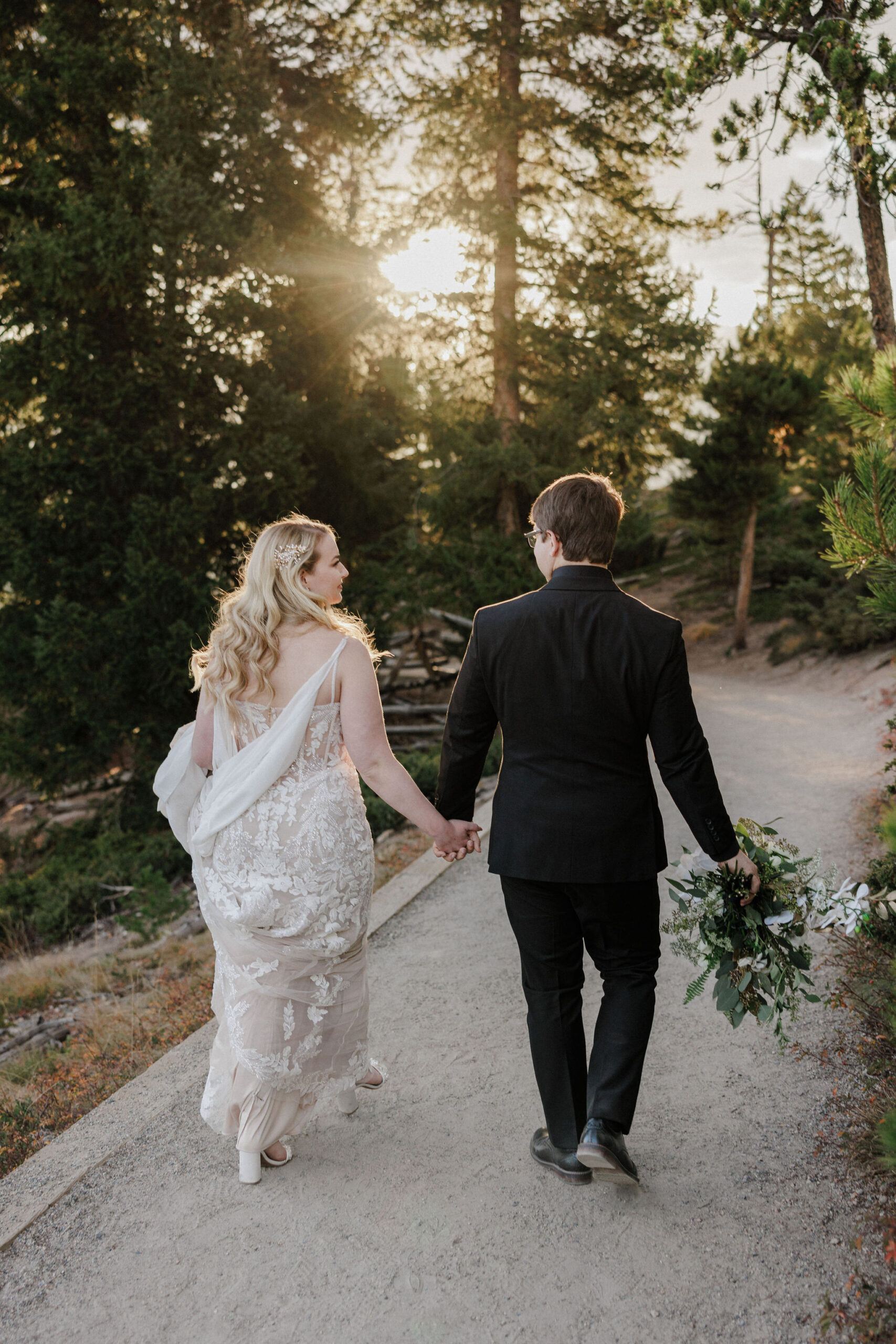 bride and groom hold hands and walk on trail in breckenridge colorado