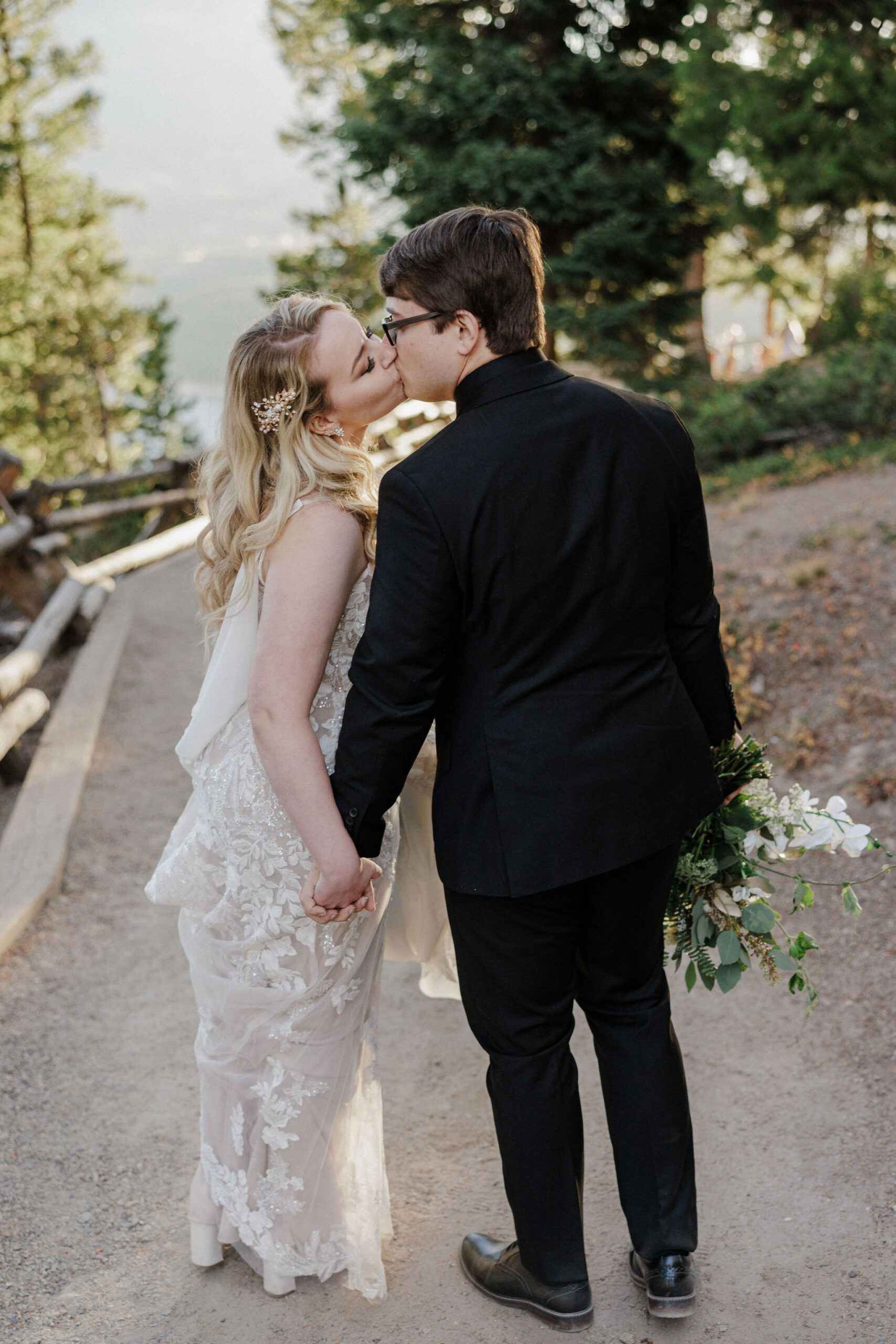 bride and groom stop on trail to share a kiss during wedding photos