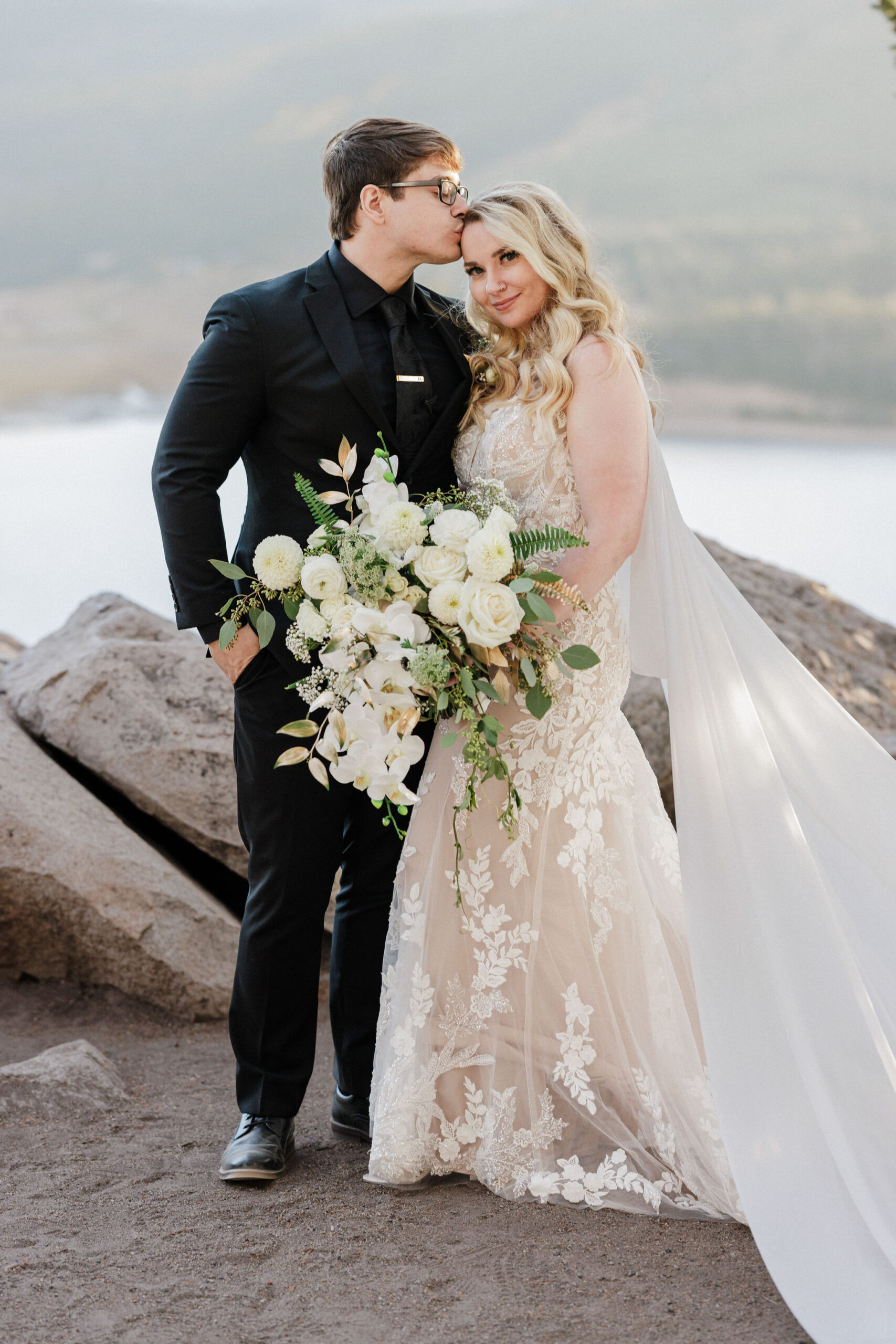 groom kisses brides head during wedding photos at sapphire point overlook