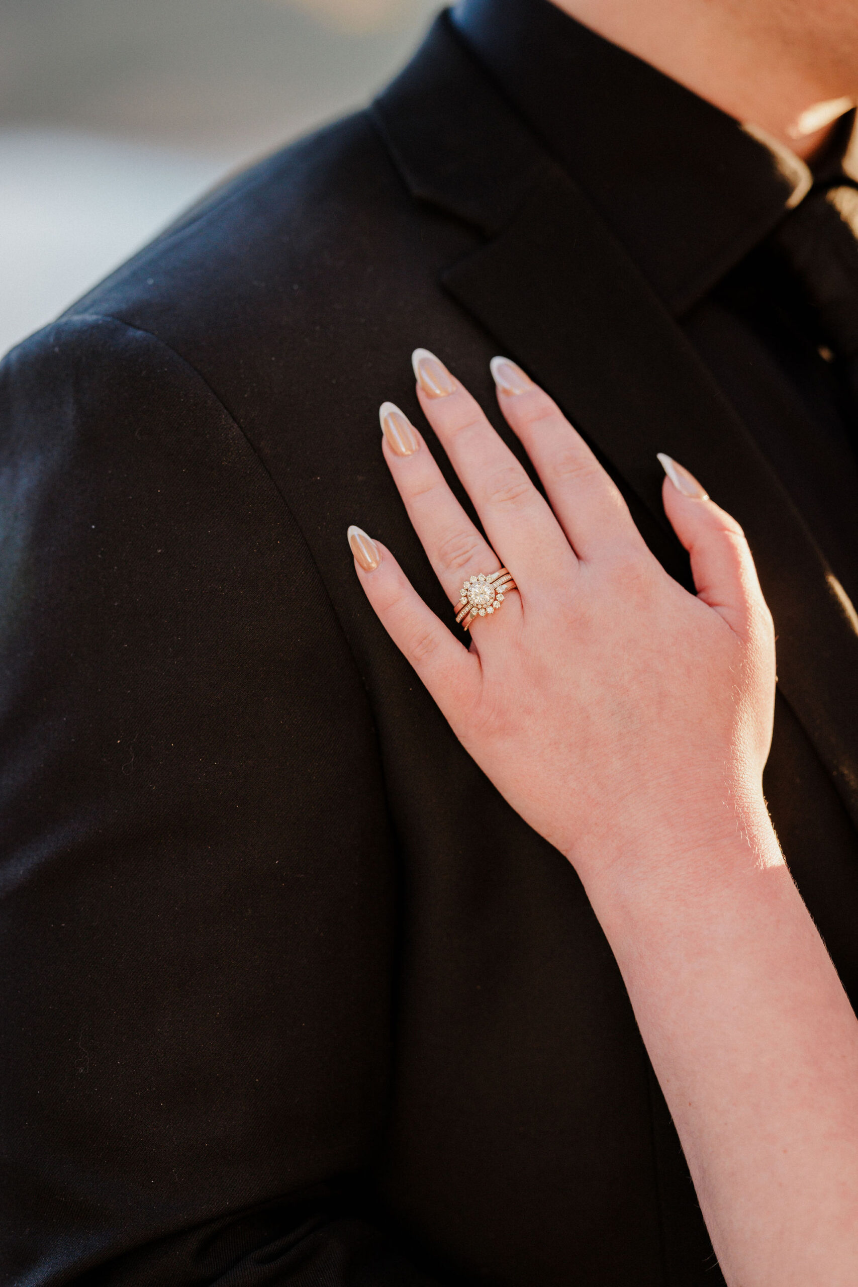 bride rests hand with wedding ring on grooms shoulder