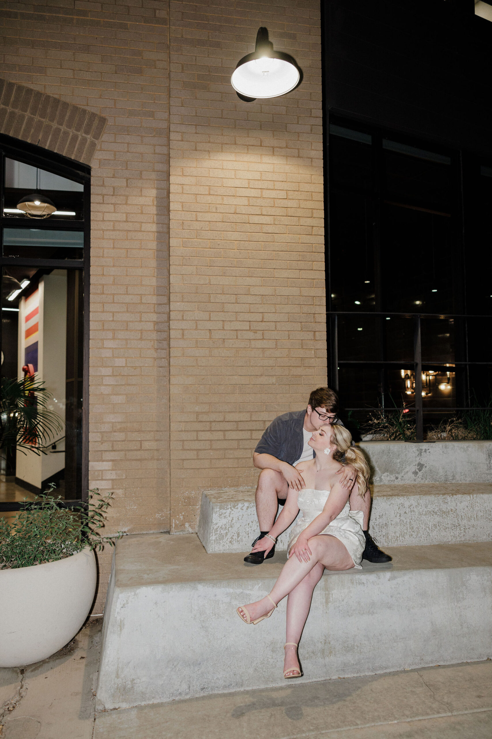 bride and groom sit on steps of hotel and kiss