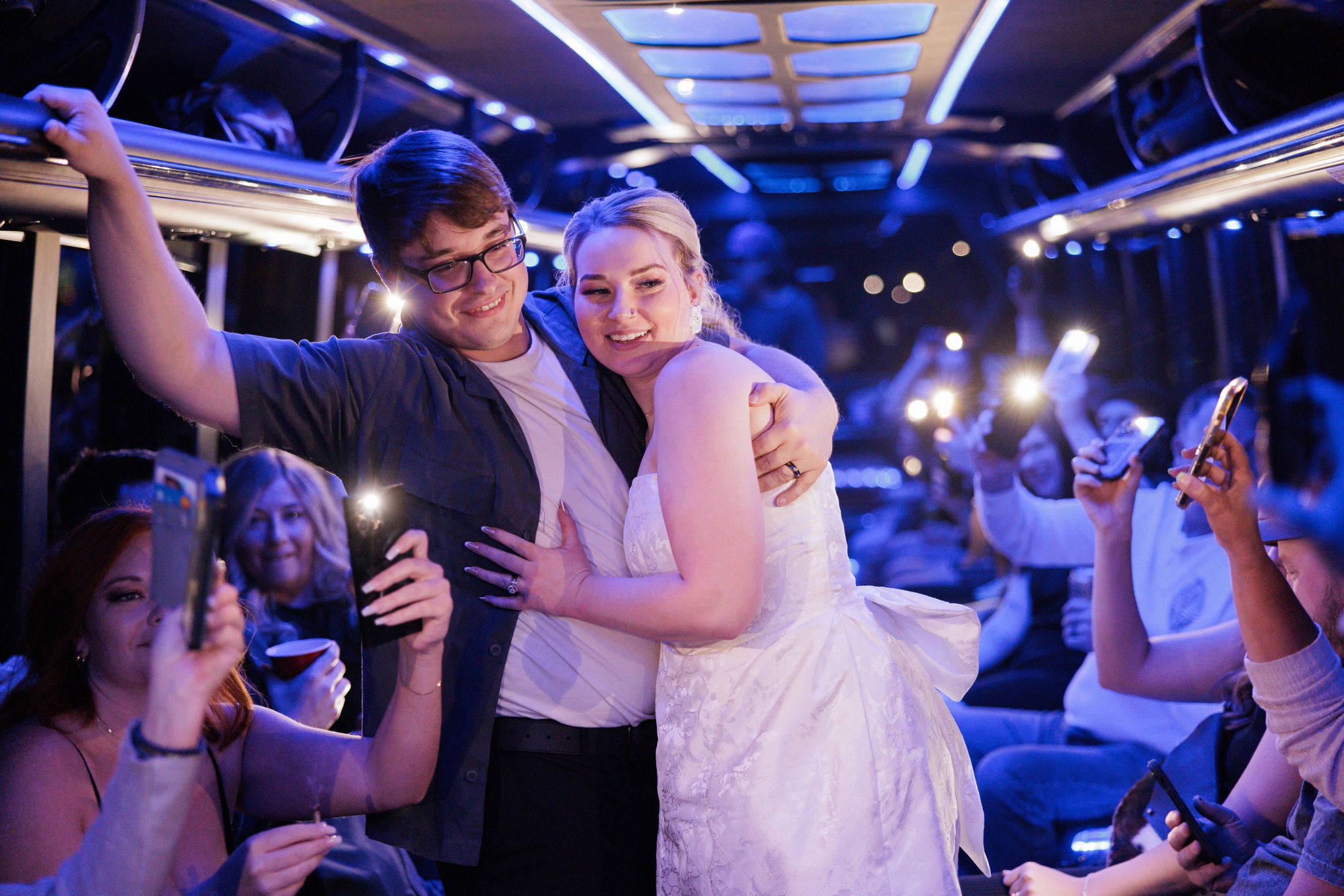 bride and groom smile and hug on party bus in denver