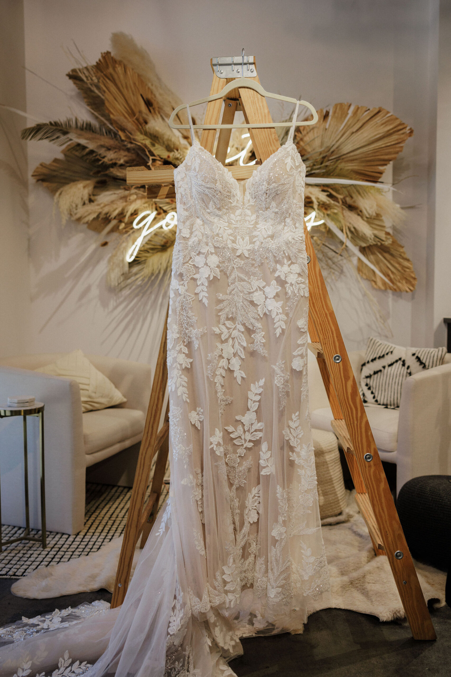 wedding dress hangs on ladder in denver beauty salon