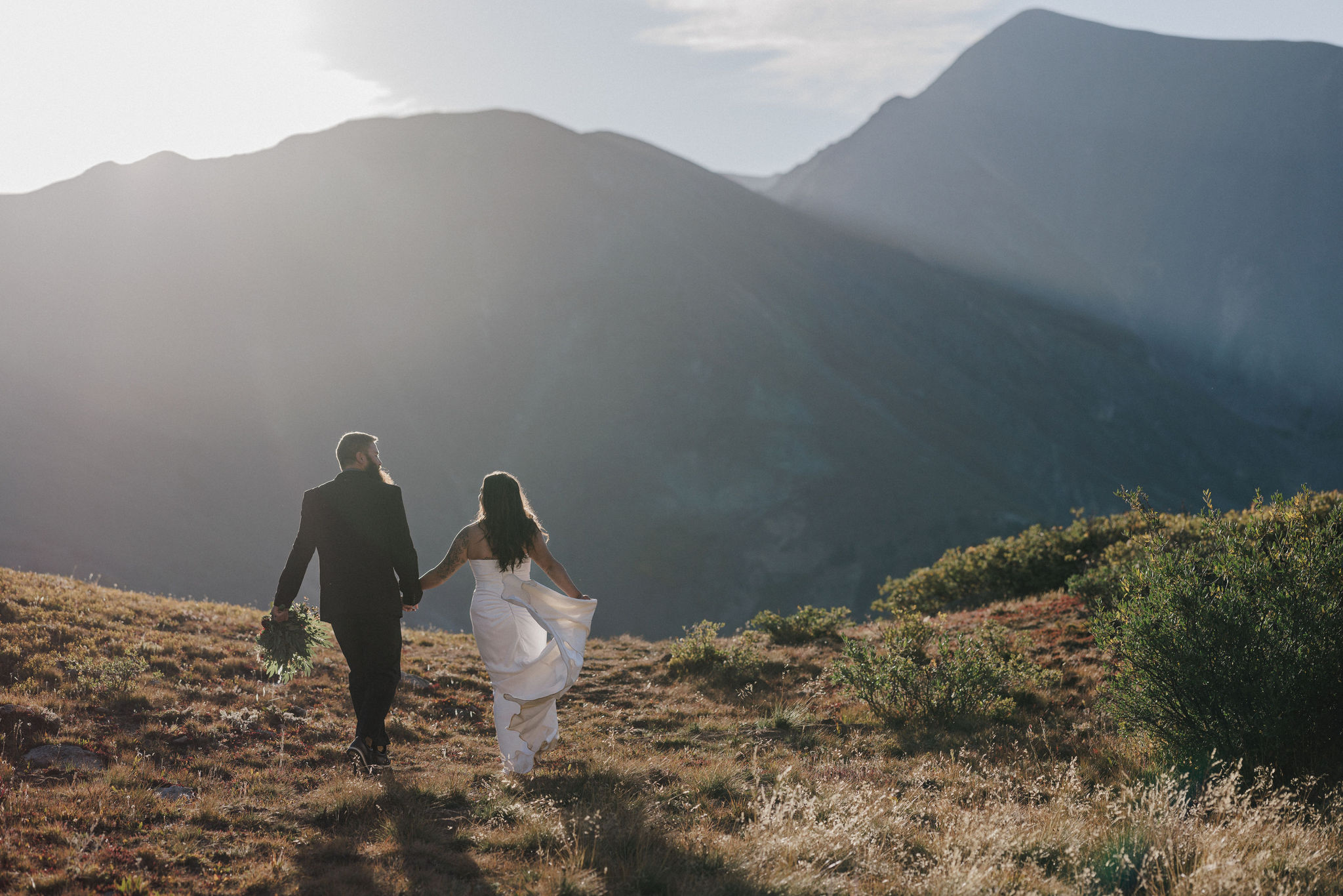 bride and groom hold hands while hiking during estes park elopement