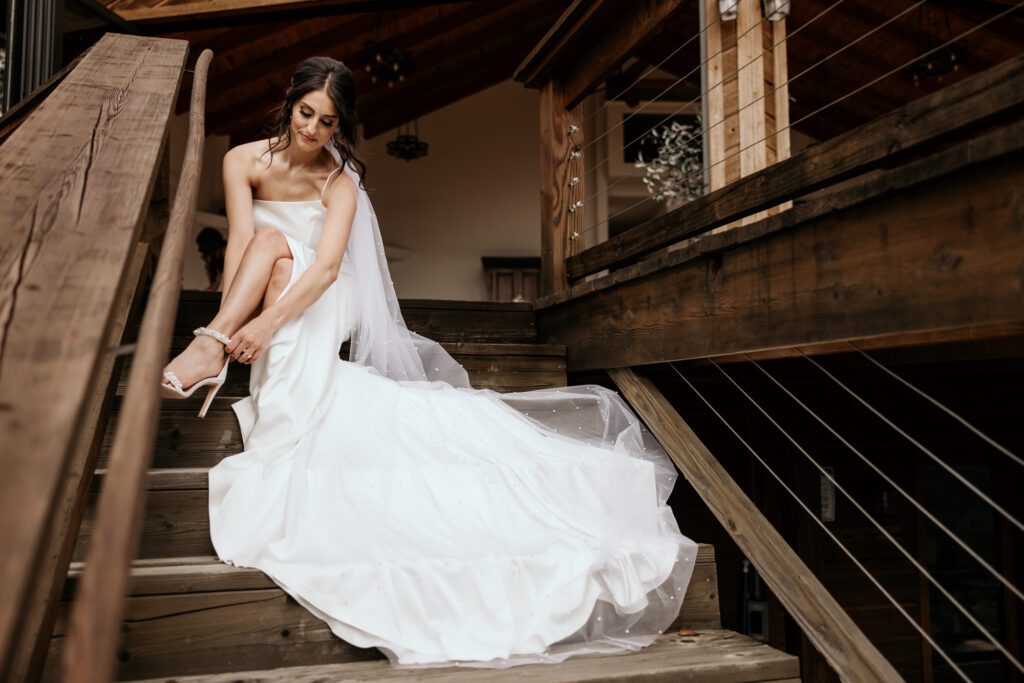 Bride puts her shoes on sitting on Airbnb cabin steps.