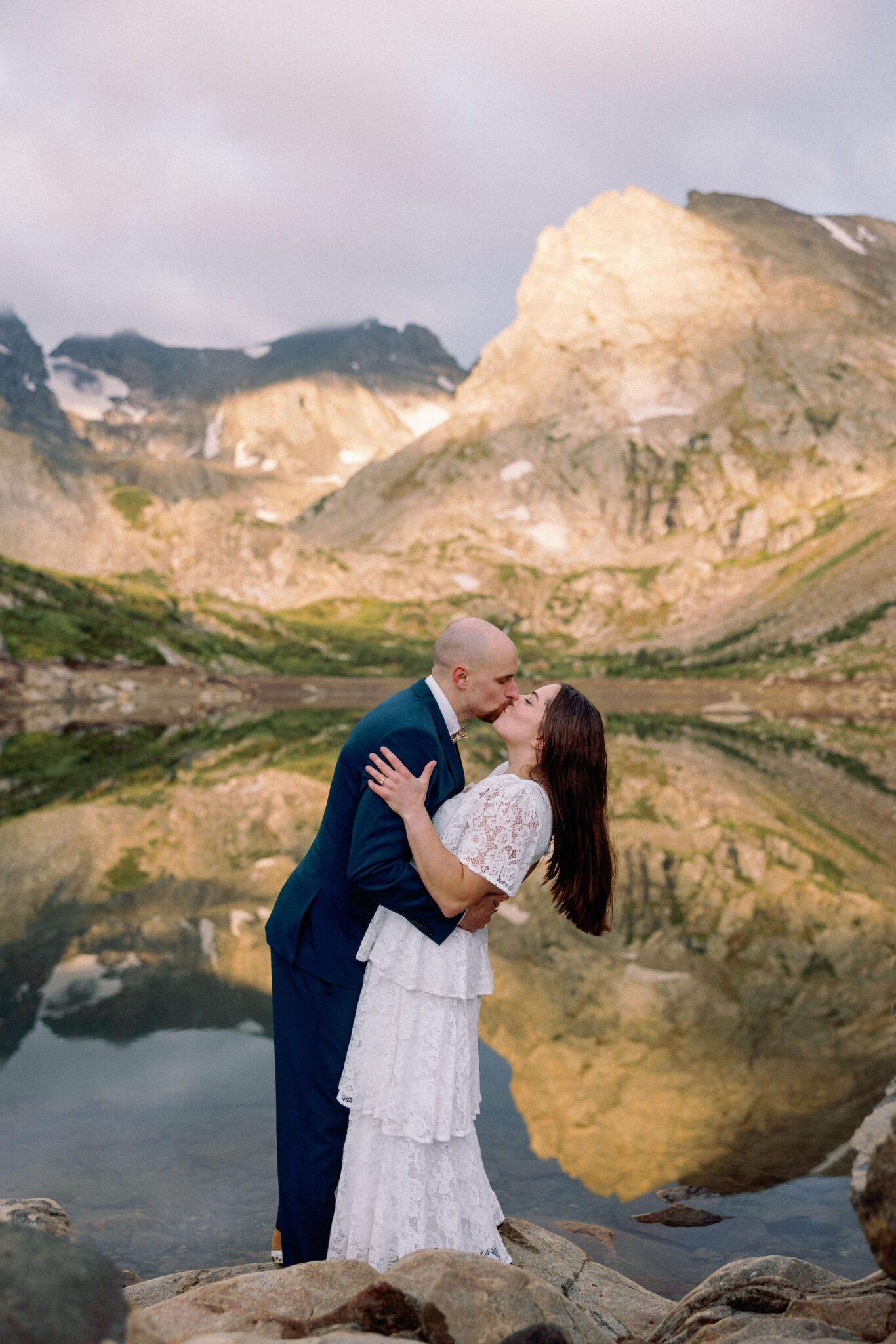 bride and groom kiss in front of alpine lake in colorado during elopement cermeony