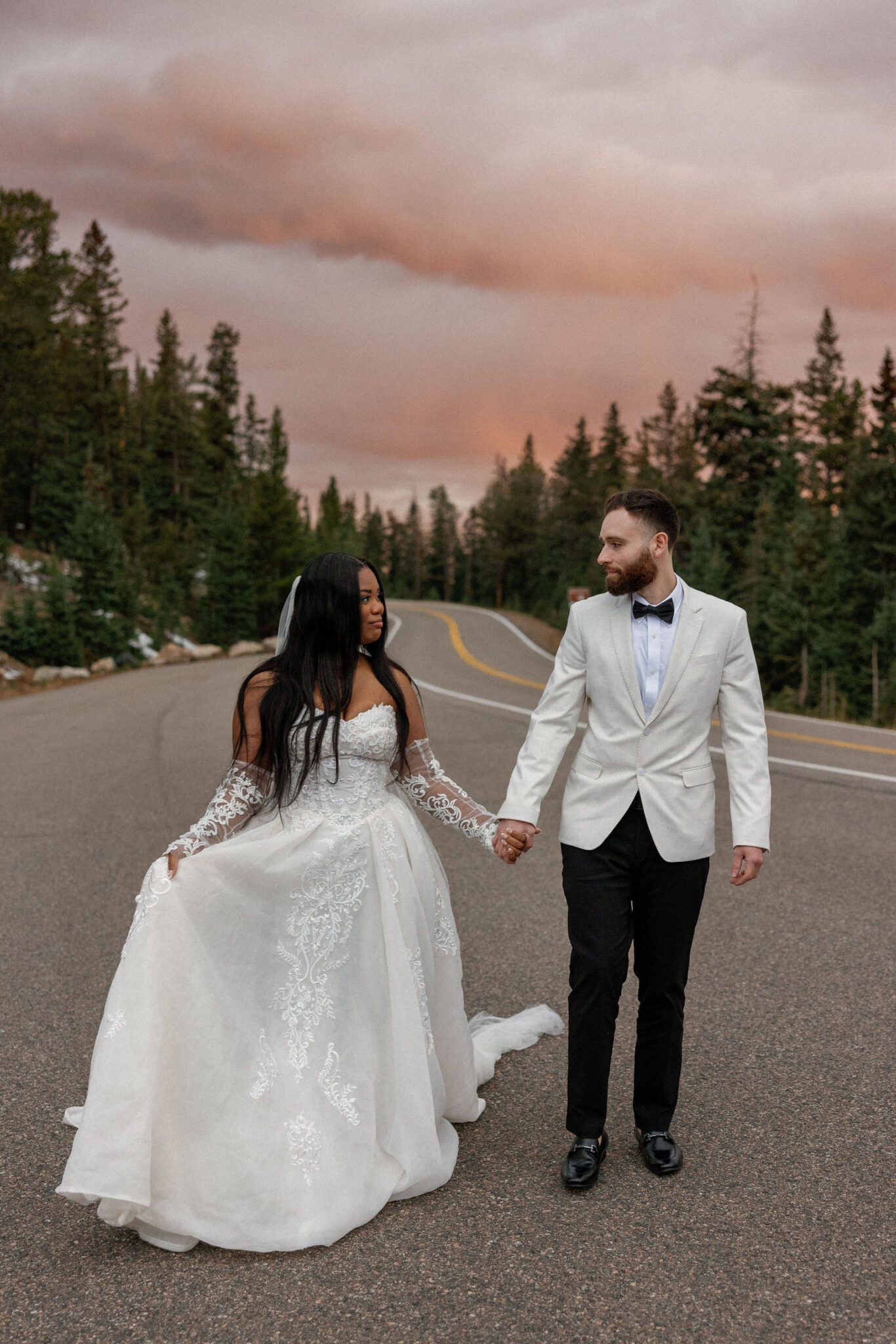 should i elope or have a wedding - bride and groom hold hands and walk down road during their colorado elopement