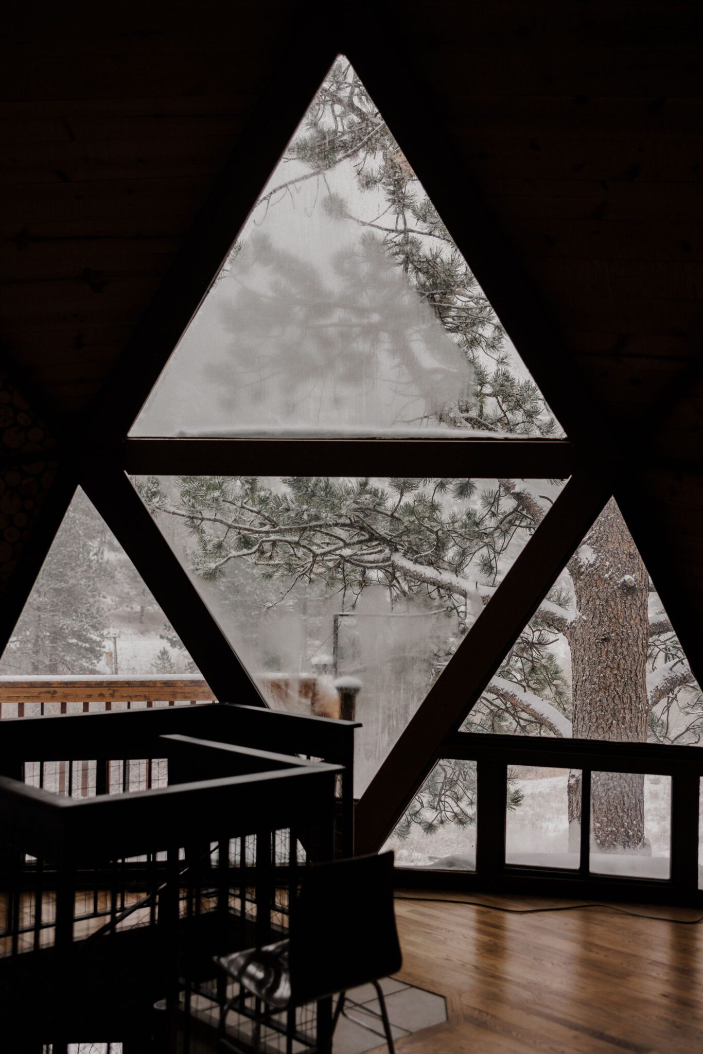 triangle window in airbnb looks out at snowy colorado winter weather