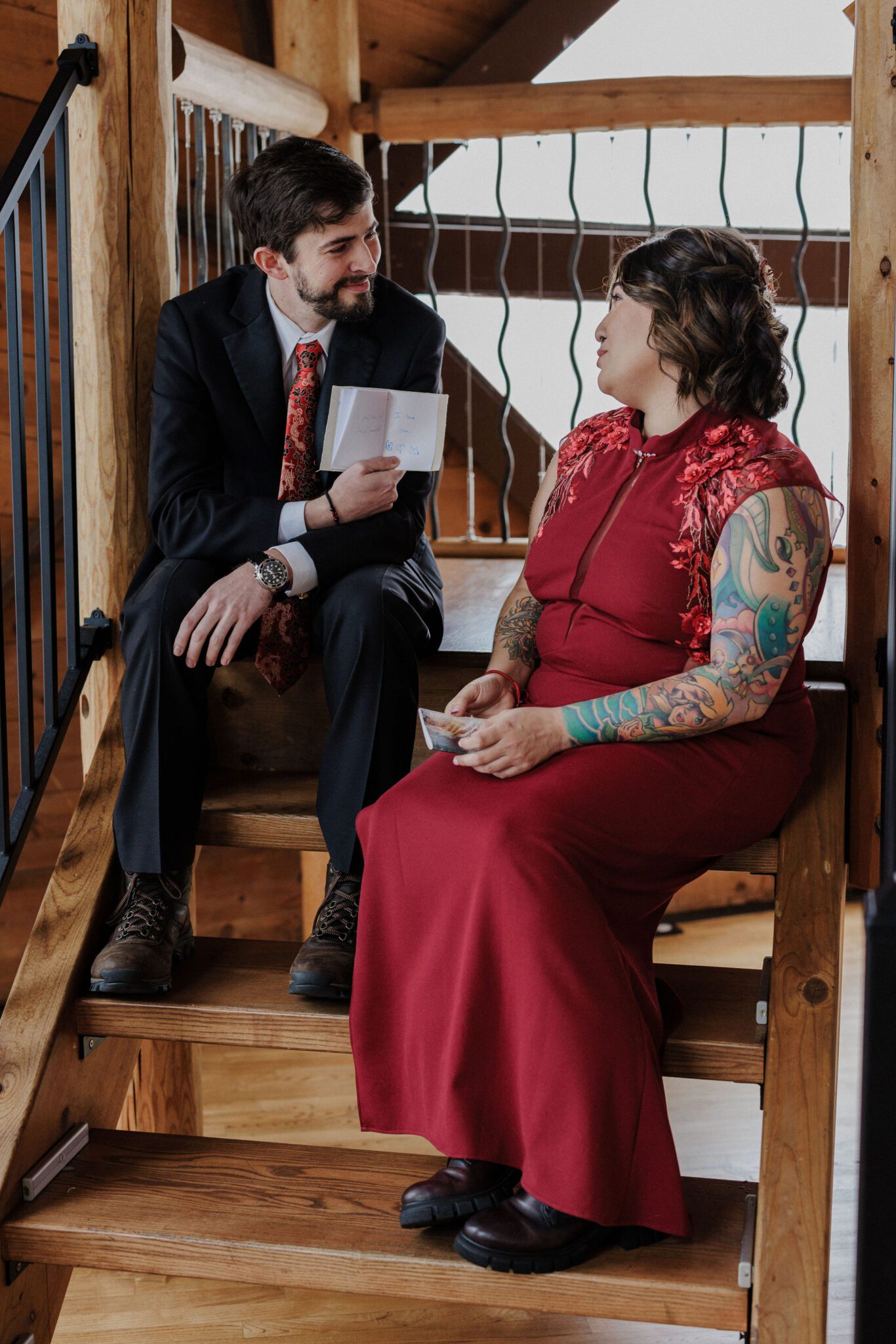 bride and groom sit on stairs in colorado airbnb and say private vows before winter elopement ceremony