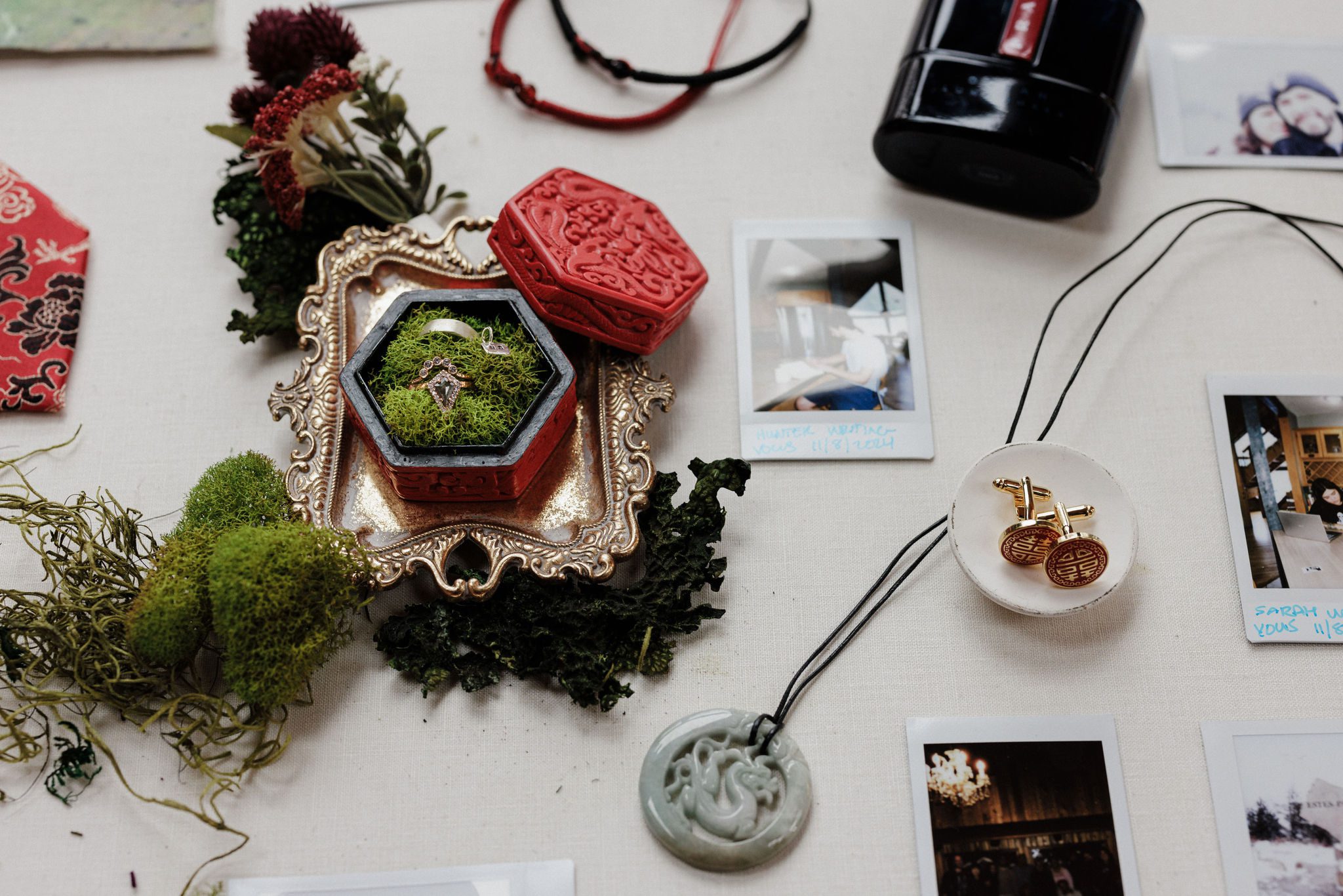 winter elopement details- wedding rings, red chinese trinket box, jewelry, chinese knot bracelets, and polaroid photos of bride and groom