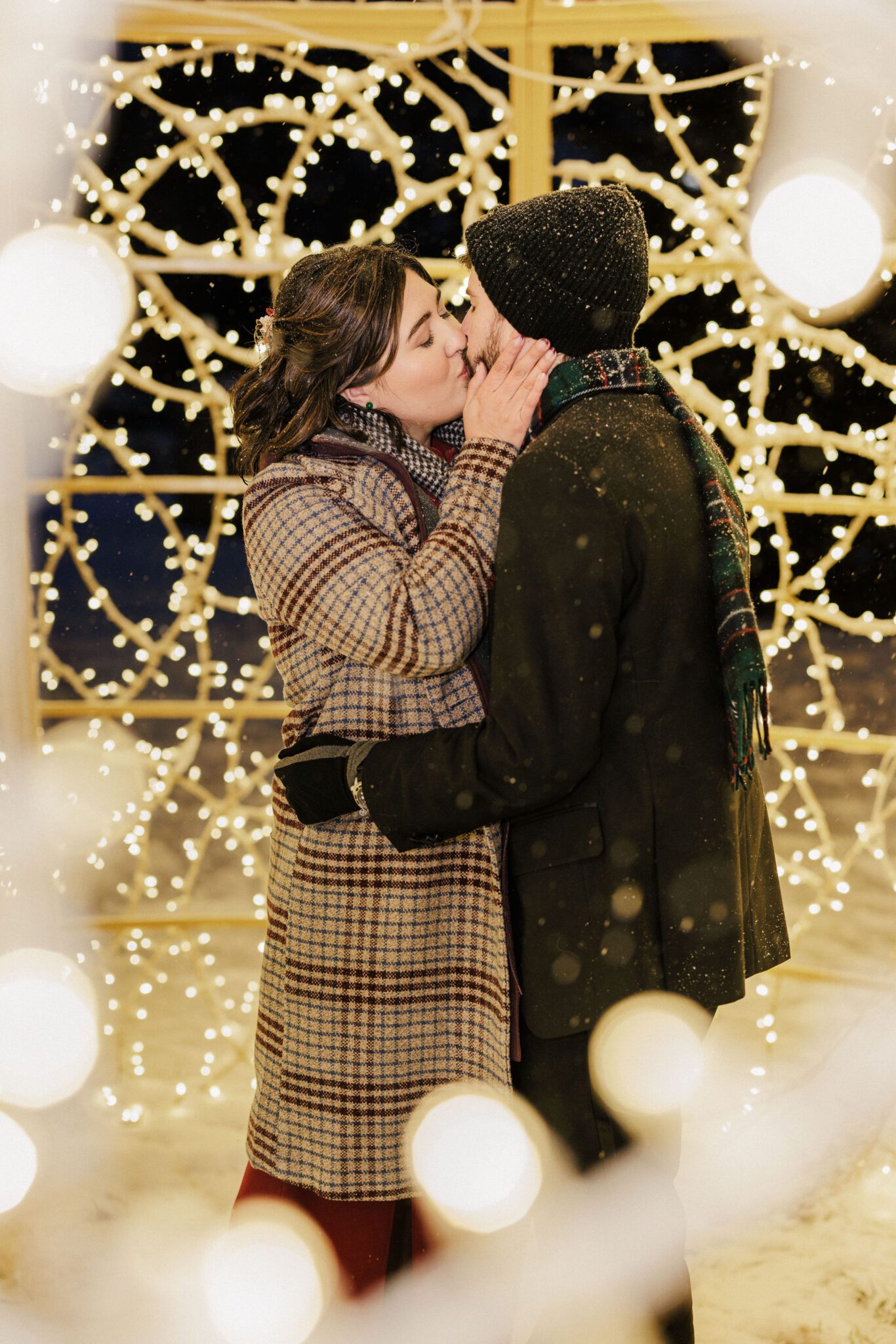 bride and groom kiss inside christmas lights display in estes park after their colorado winter elopement