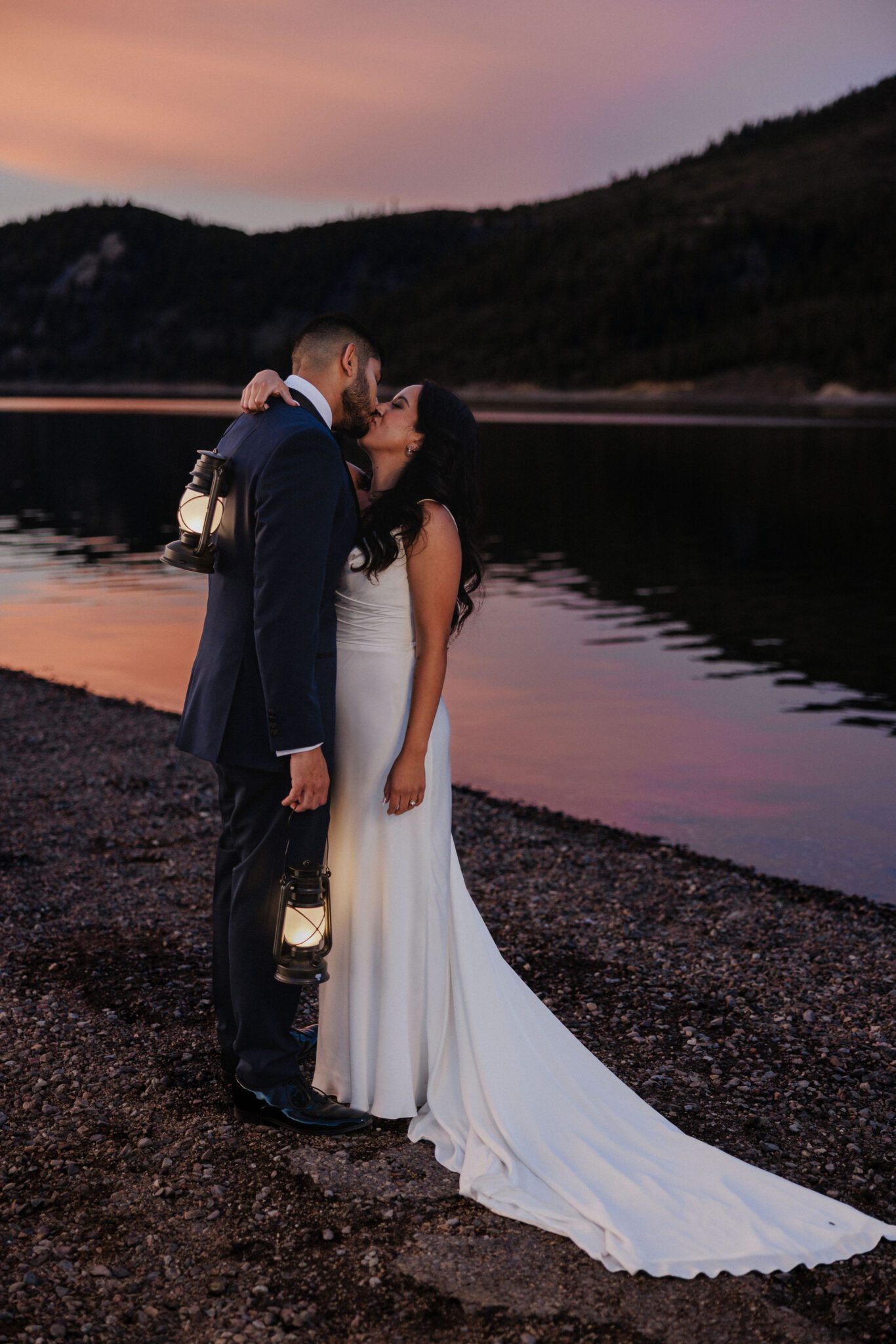 bride and groom kiss holding lanterns during wedding photos