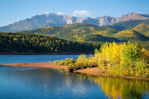 pikes peak sits behind mountain lake and yellow aspens