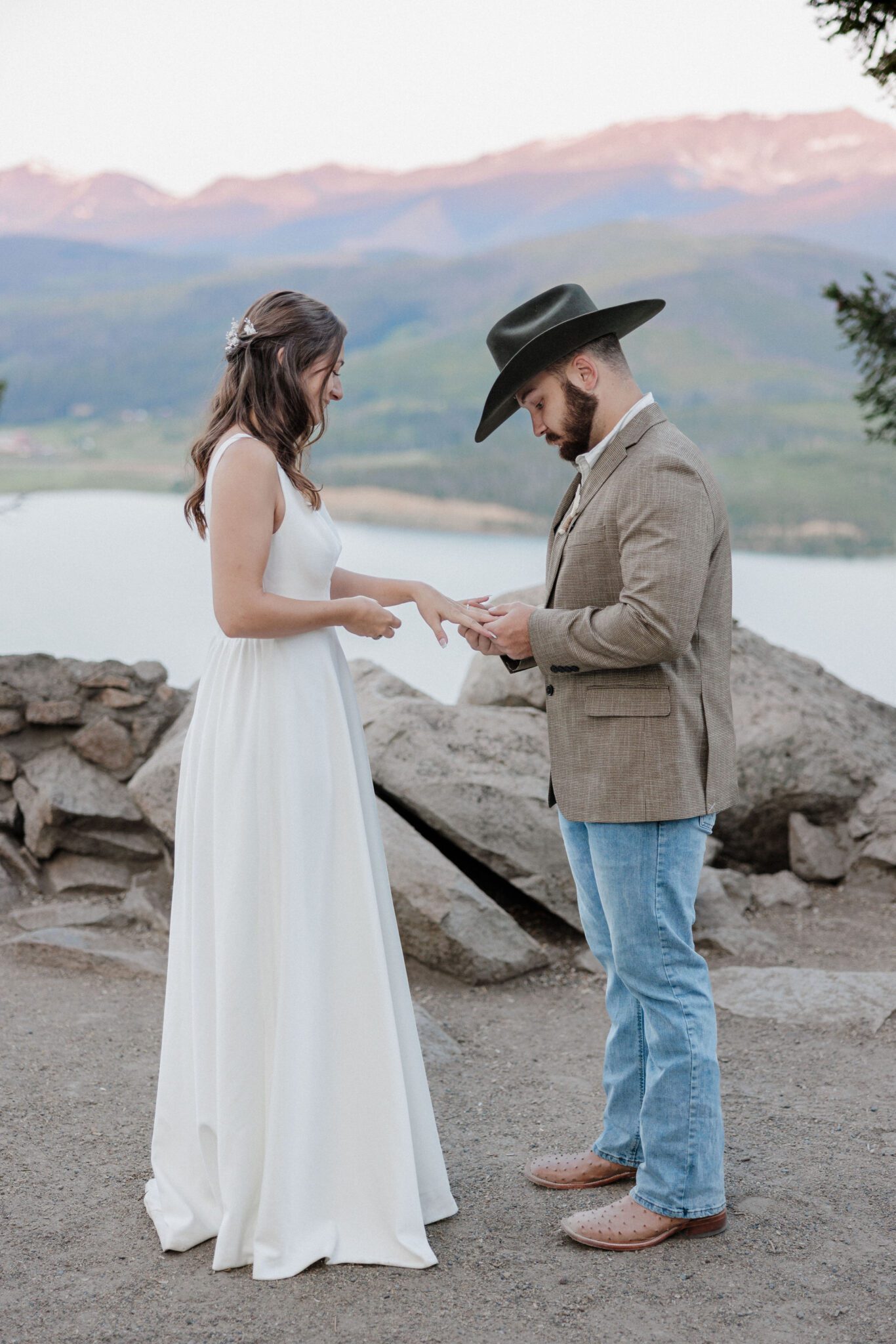 groom puts wedding ring on bride during colorado elopement ceremony at sapphire point overlook