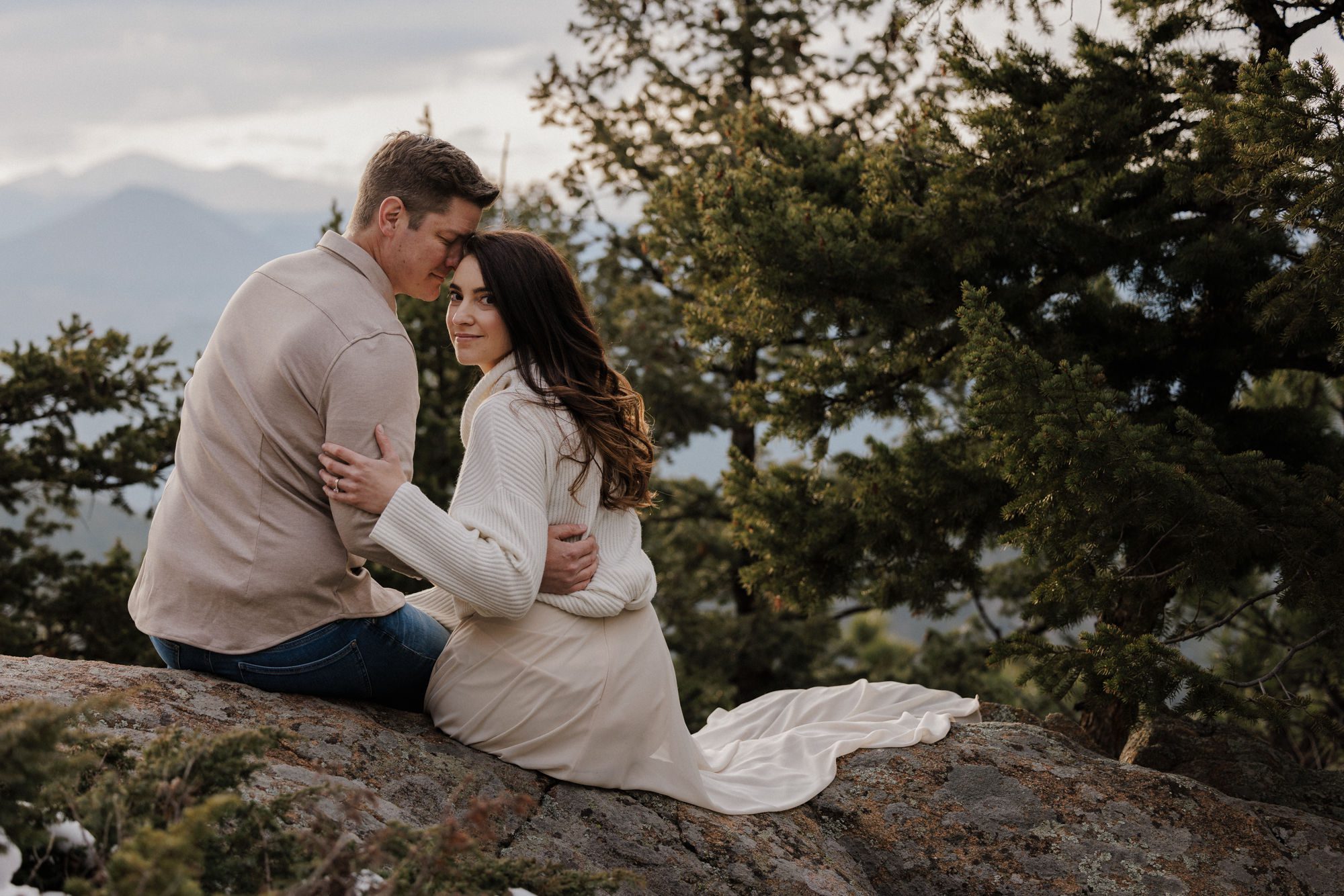 bride and groom sit on rock and look back at photographer during colorado elopement