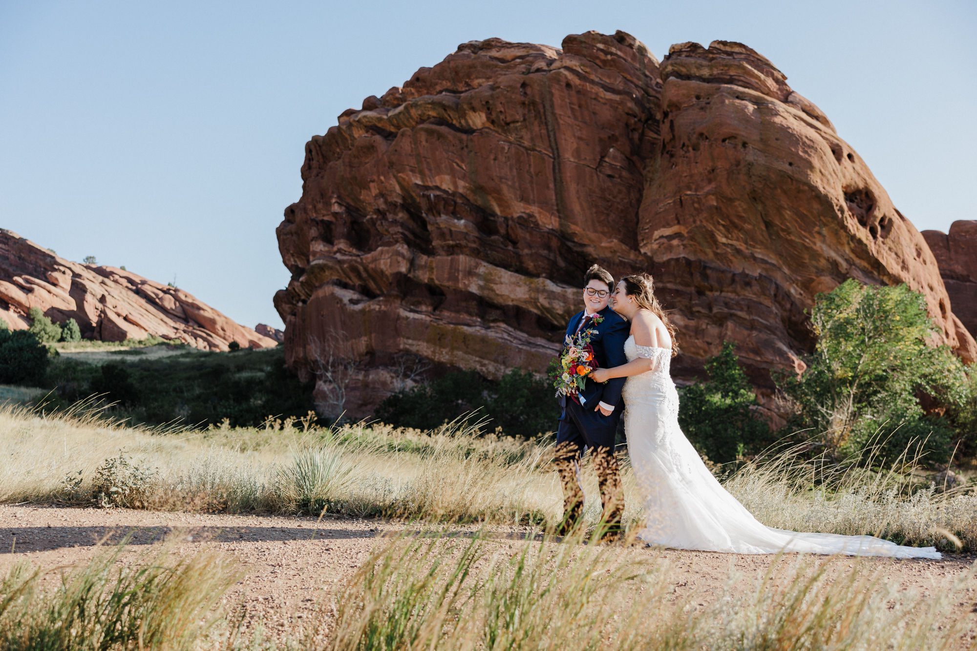 two brides smile and embrace during elopement photos in colorado's red rocks park