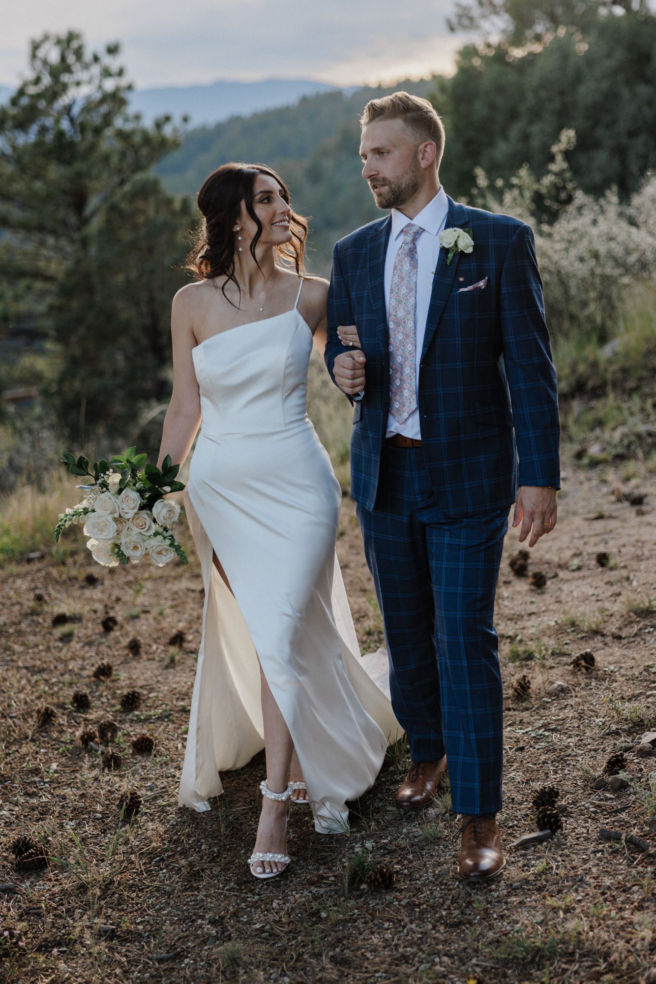 bride holds grooms arm and smiles at him during colorado forest wedding