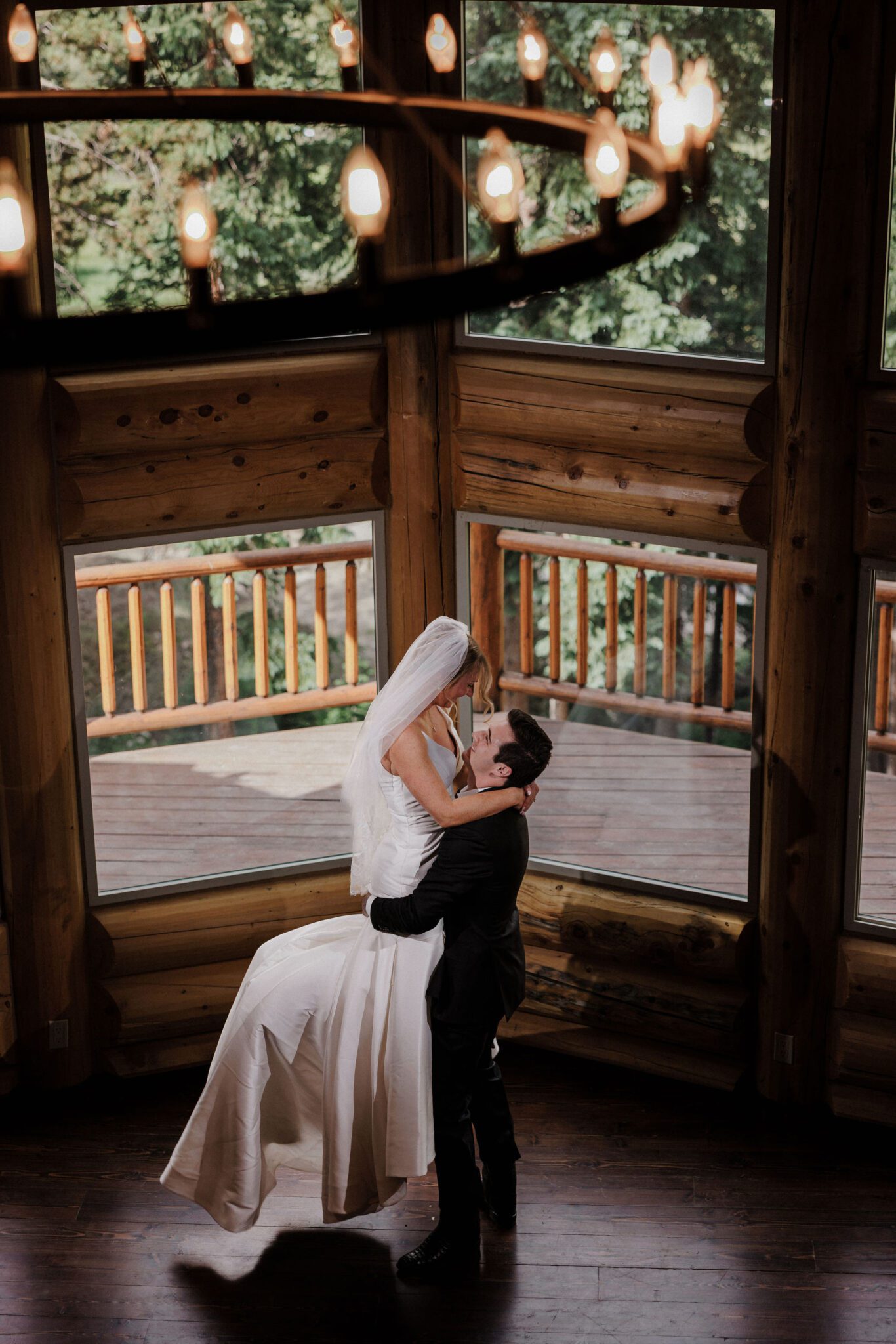 groom lifts bride up in front of big windows at an airbnb during colorado elopement