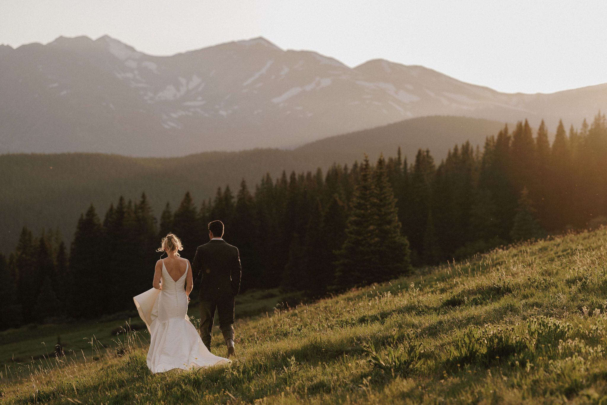 after choosing the adventure colorado elopement package, bride and groom hold hands and walk down the mountain during sunset photos