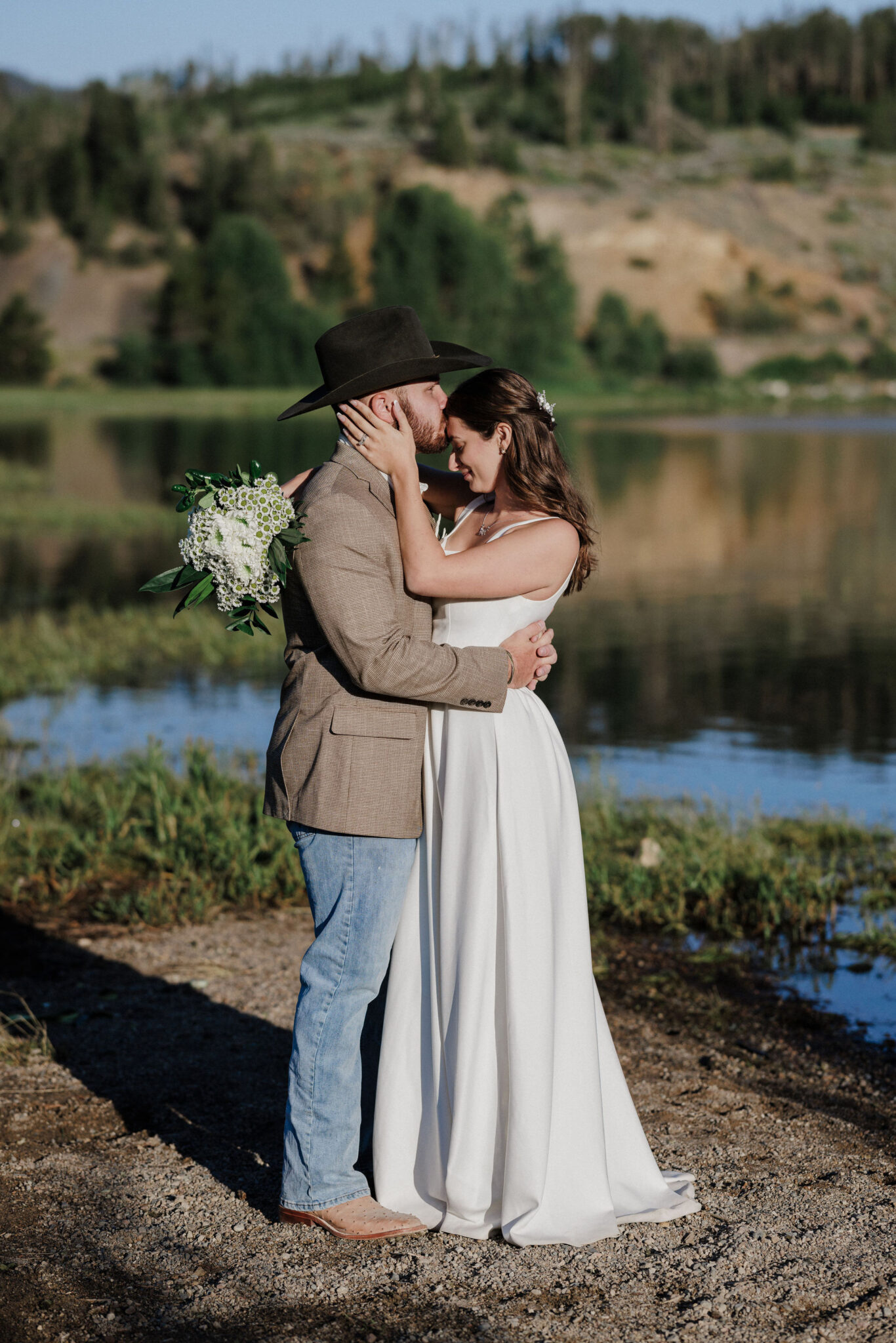 bride and groom pose for photos during colorado mountain lake wedding