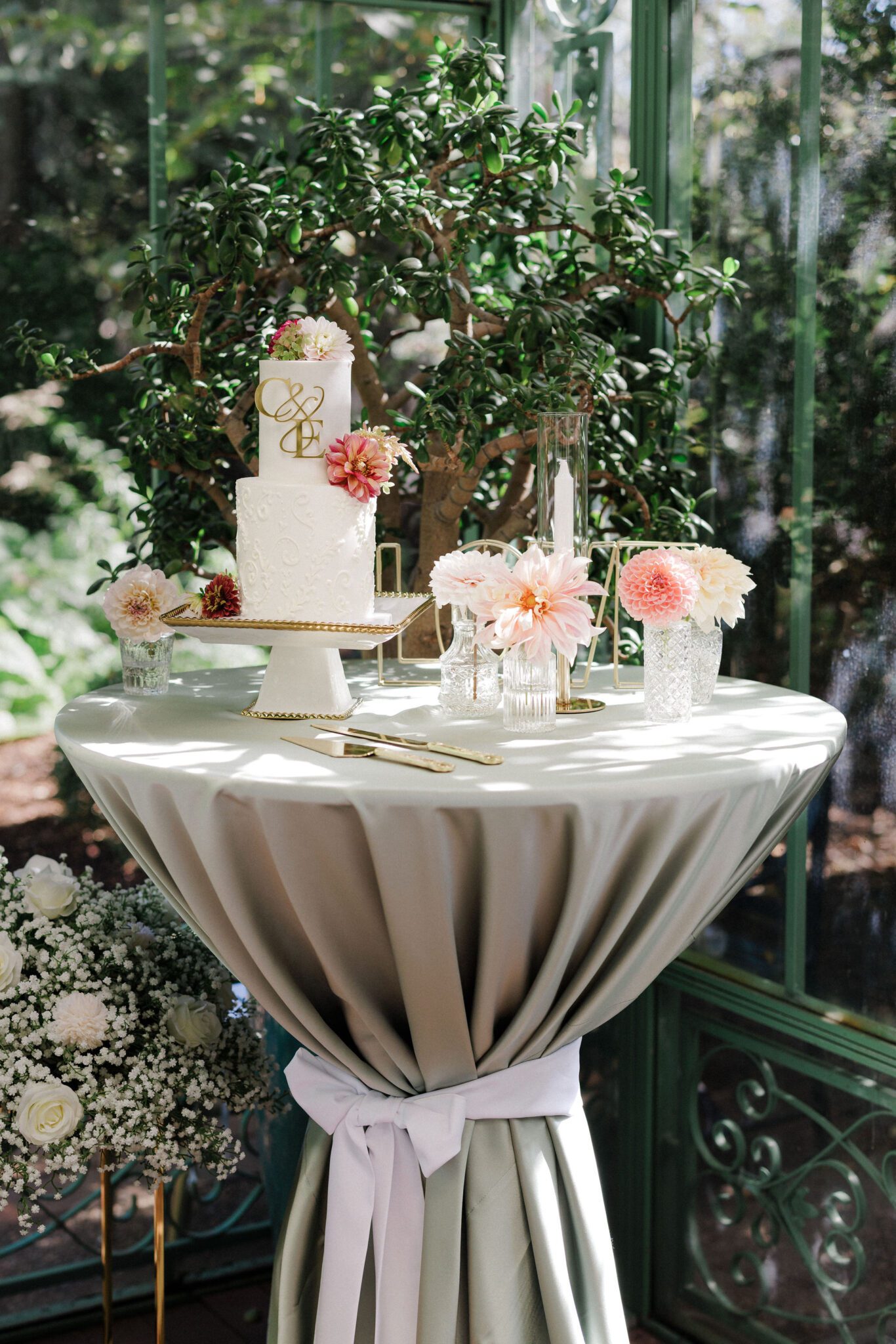 cake sits on a table with plants behind it at the denver botanic gardens, a colorado summer wedding venue
