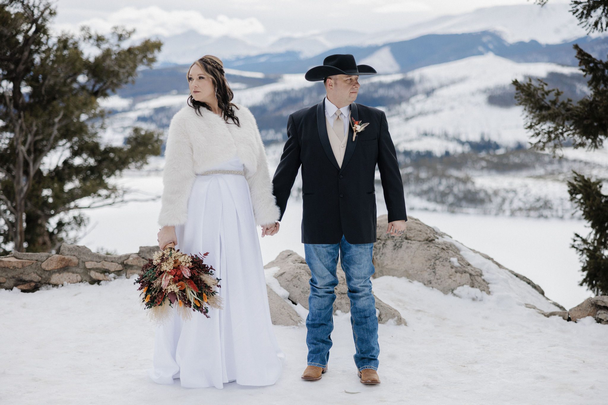 bride and groom hold hands while taking wedding photos during their mountain lake wedding in colorado