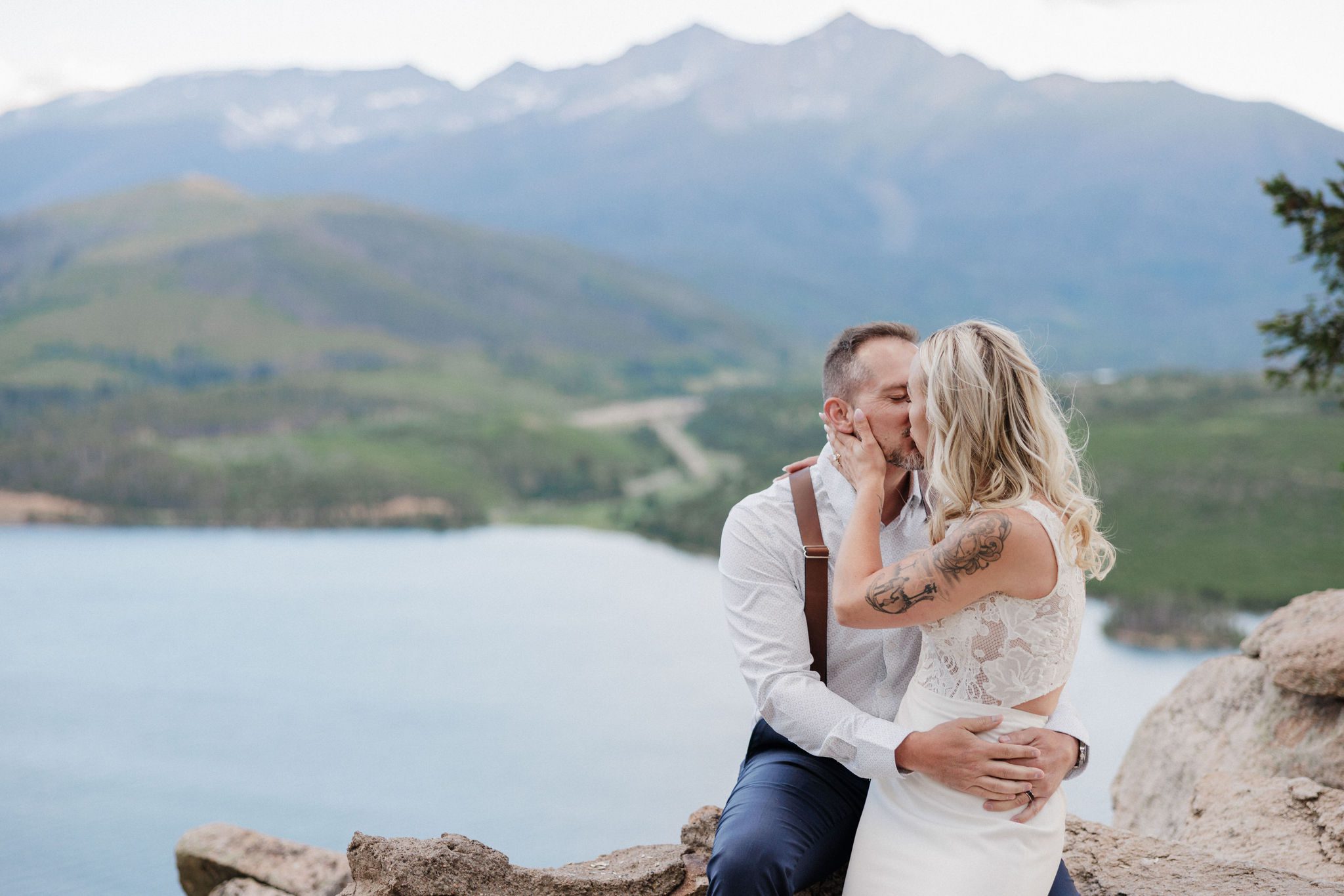 bride and groom kiss while sitting on rocky ledge at sapphire point overlook 