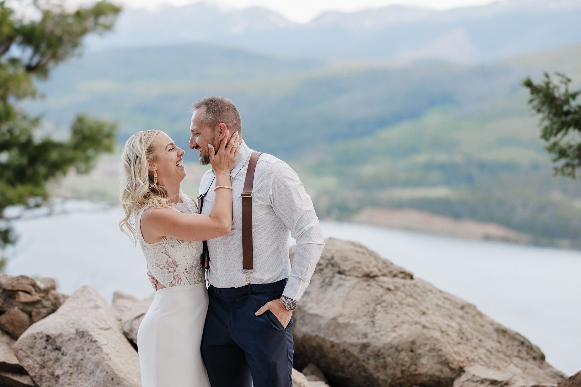 bride and groom smile as they pose for photographer during colorado summer wedding