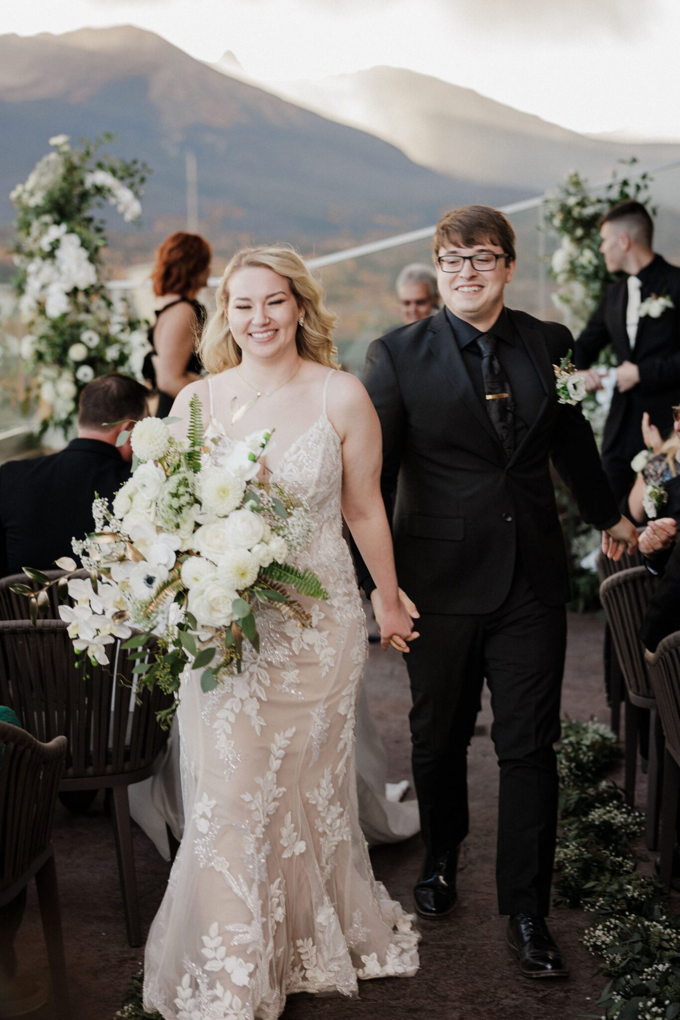 bride and groom smile and hold hands as they walk down the aisle during their breckenridge elopement wedding