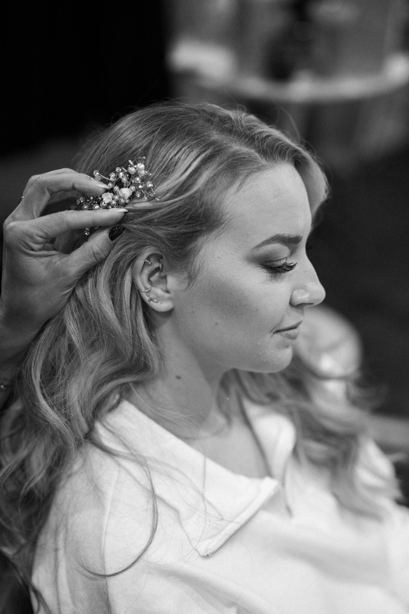 bride sits as her hair and makeup artist does her hair