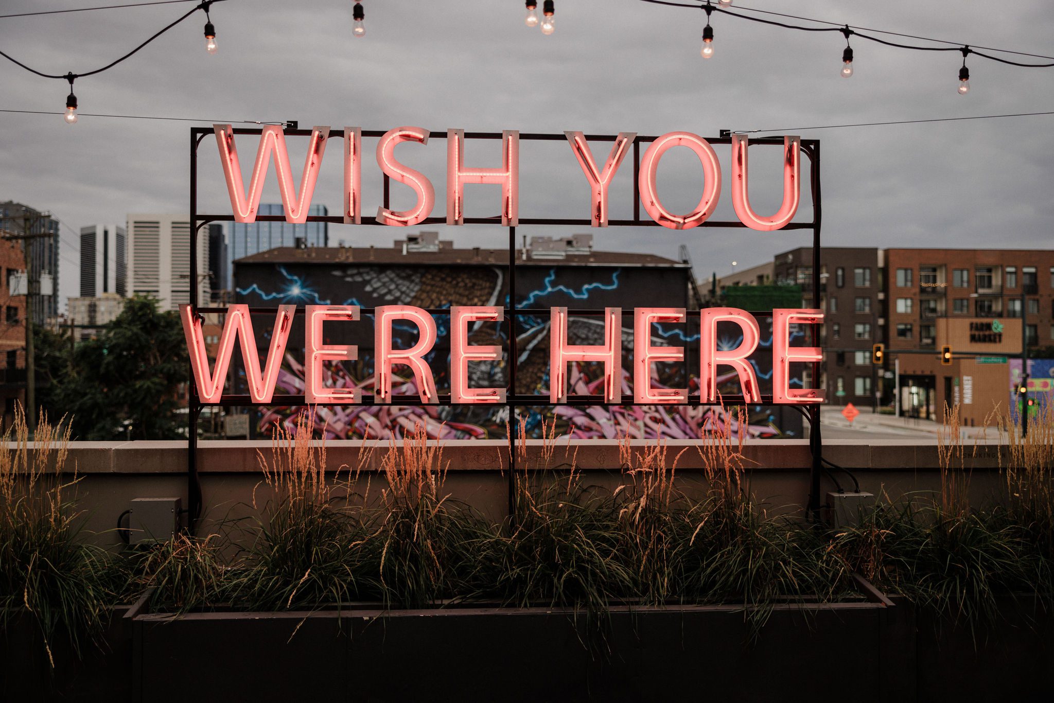 'wish you were here' neon sign lights up red at denver micro wedding venue, the ramble hotel