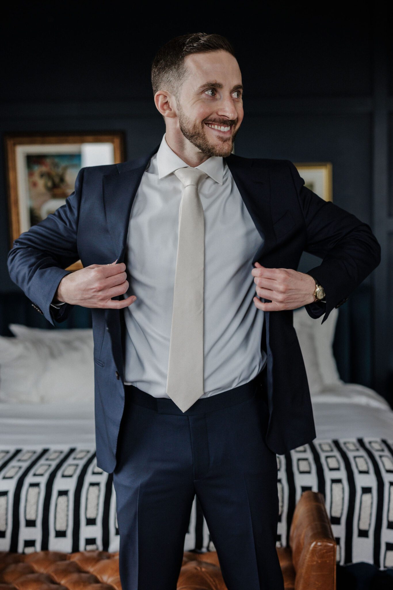 groom puts suit jacket on while getting ready in denver micro wedding wedding venue, the ramble hotel