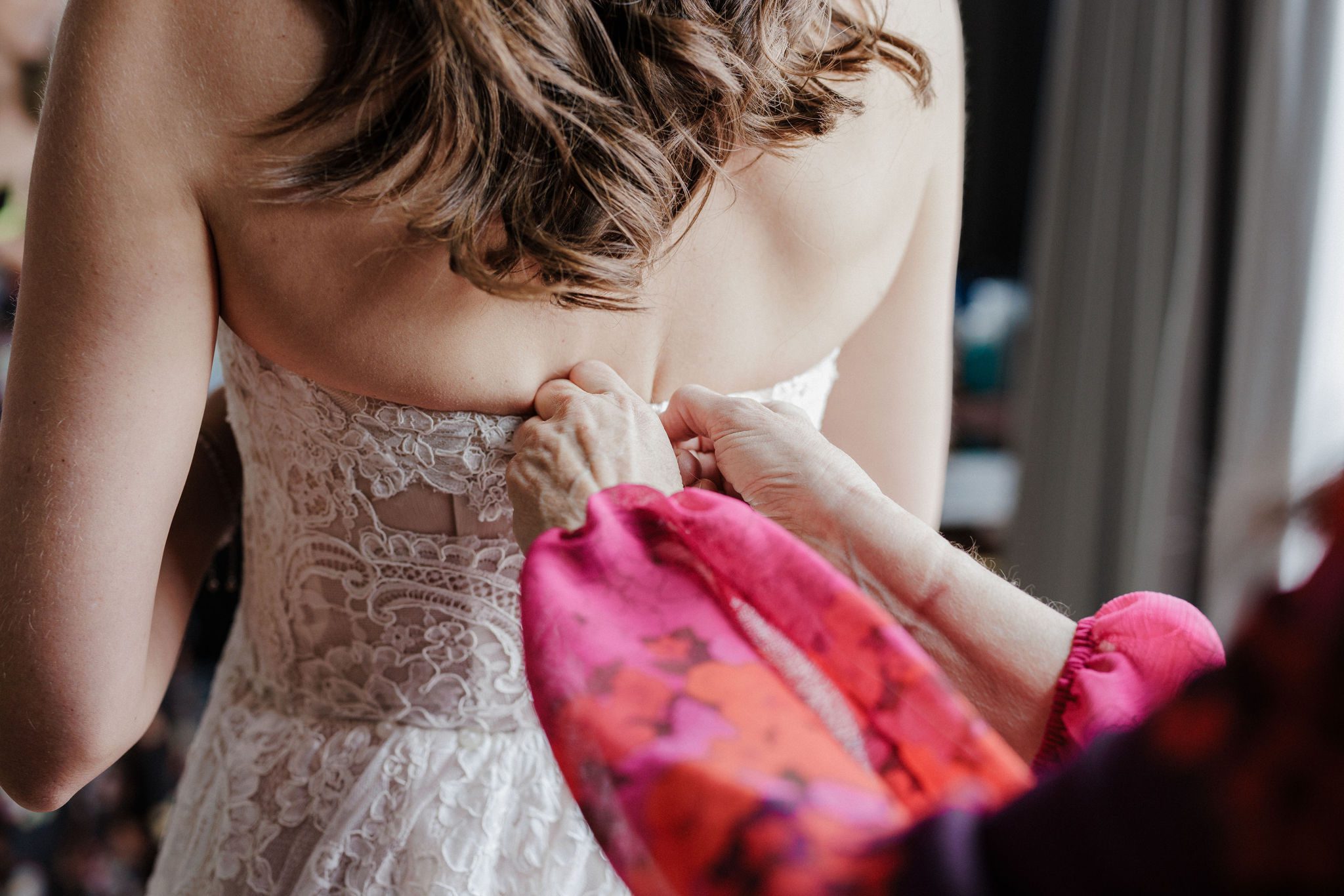 bride gets help putting wedding dress on before ramble hotel wedding ceremony