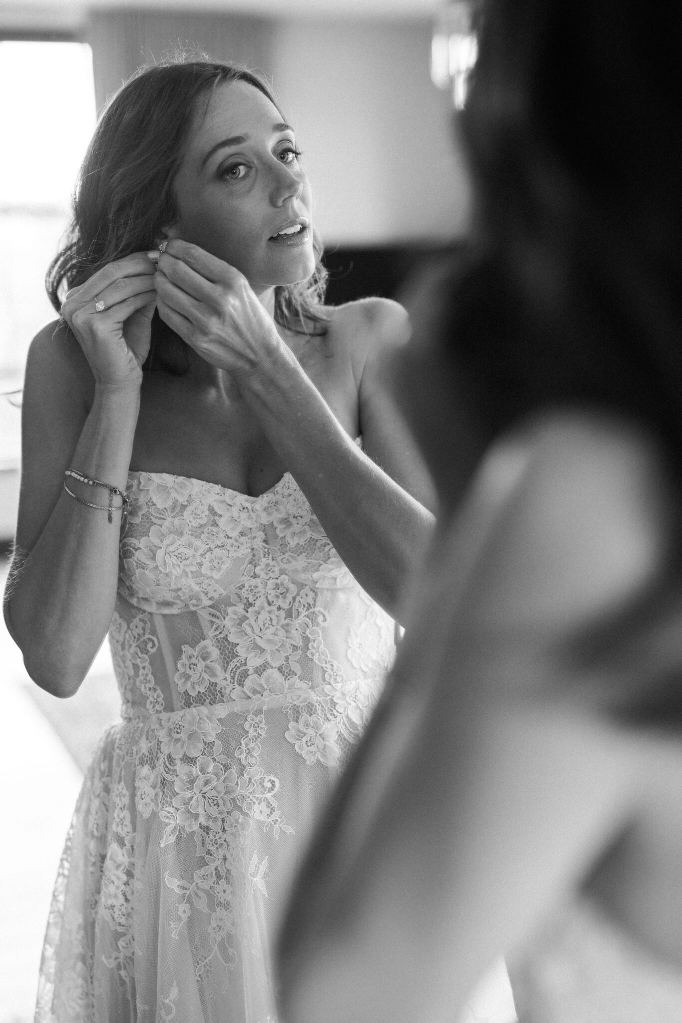 bride puts earrings on in suite at the ramble hotel before wedding ceremony