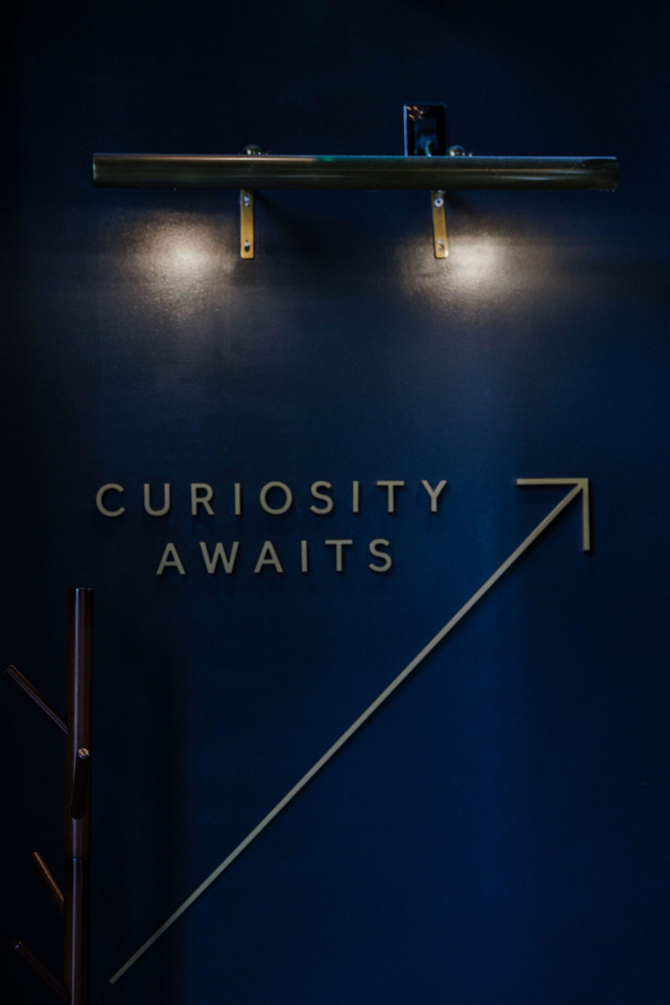 'curiosity awaits' sign with arrow points up stairwell at colorado summer wedding venue