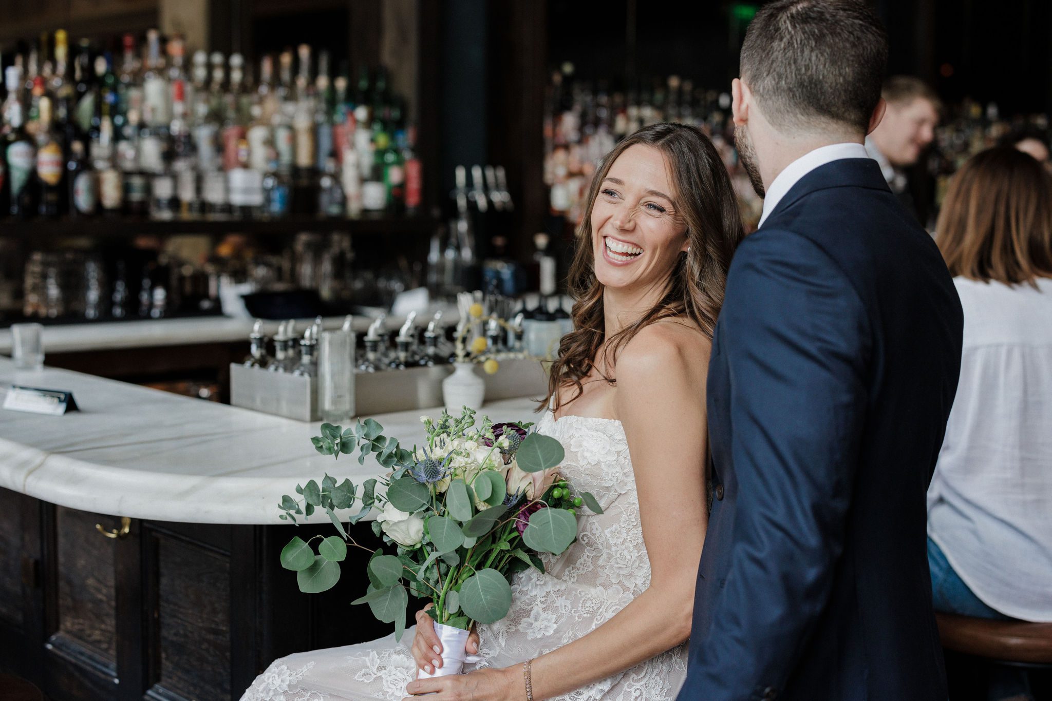 bride and groom sit at bar of the ramble hotel during wedding photos