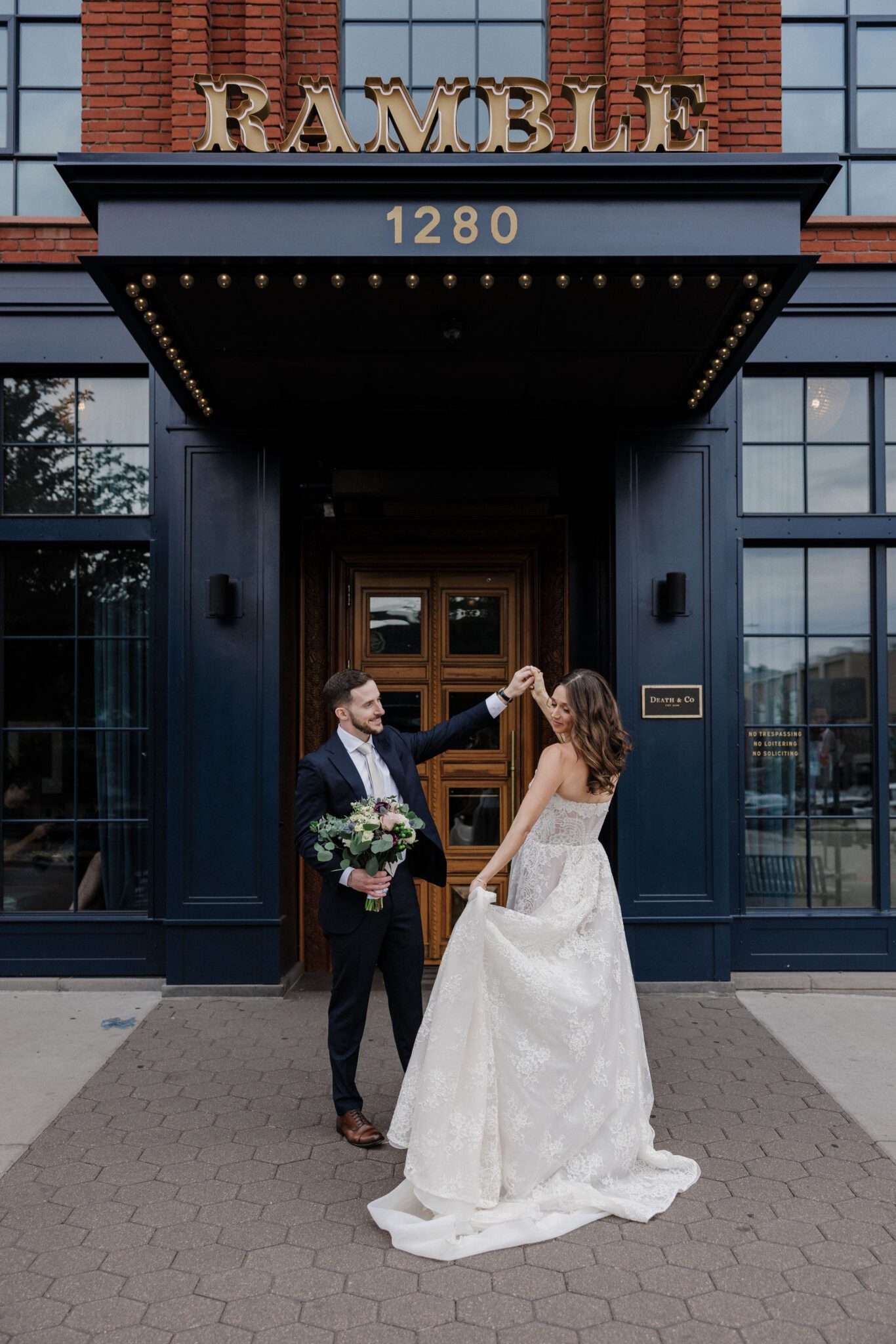 groom twirls bride in front of the ramble hotel, a denver summer wedding venue