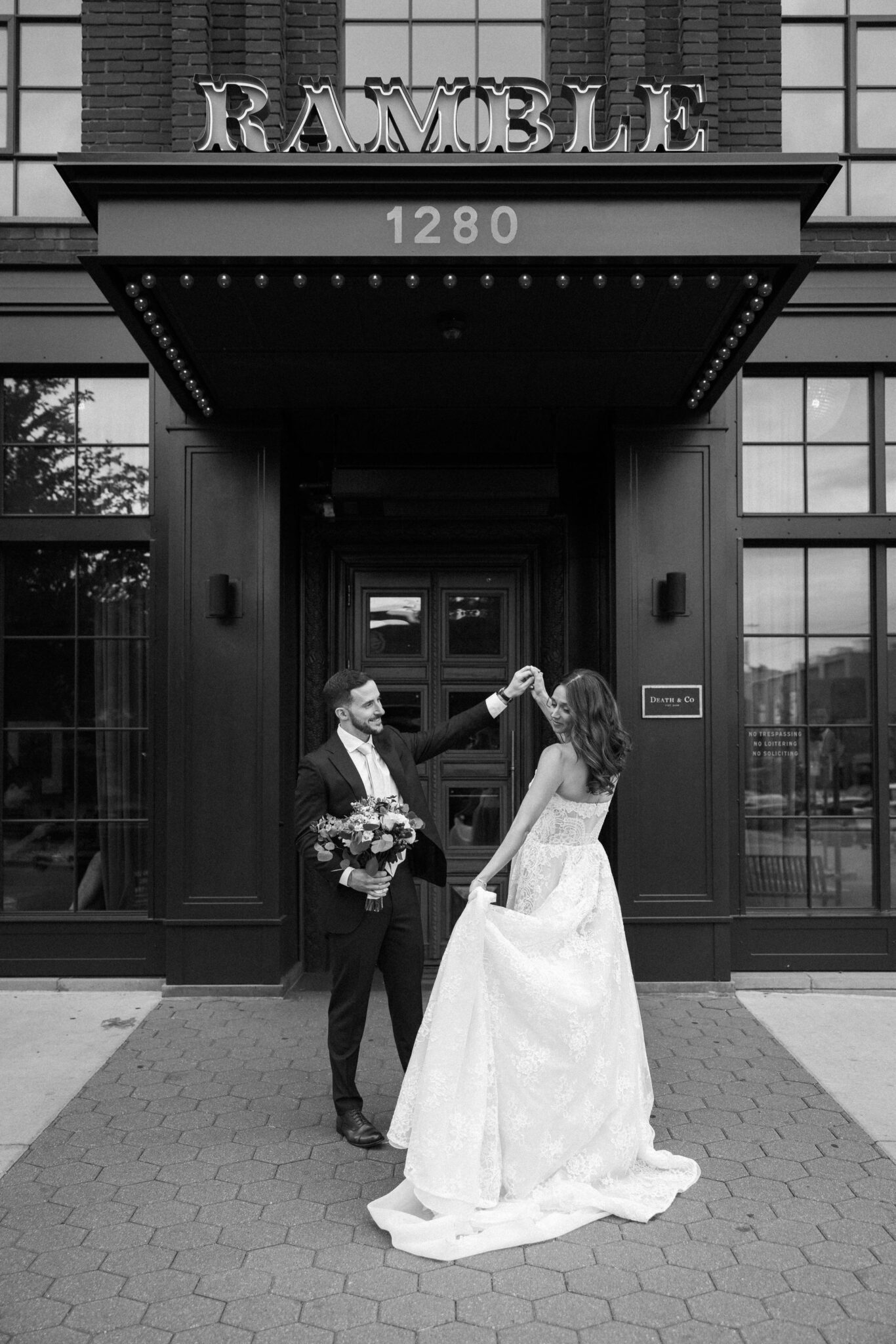 groom twirls bride in front of the entrance to the ramble hotel, a denver micro wedding venue