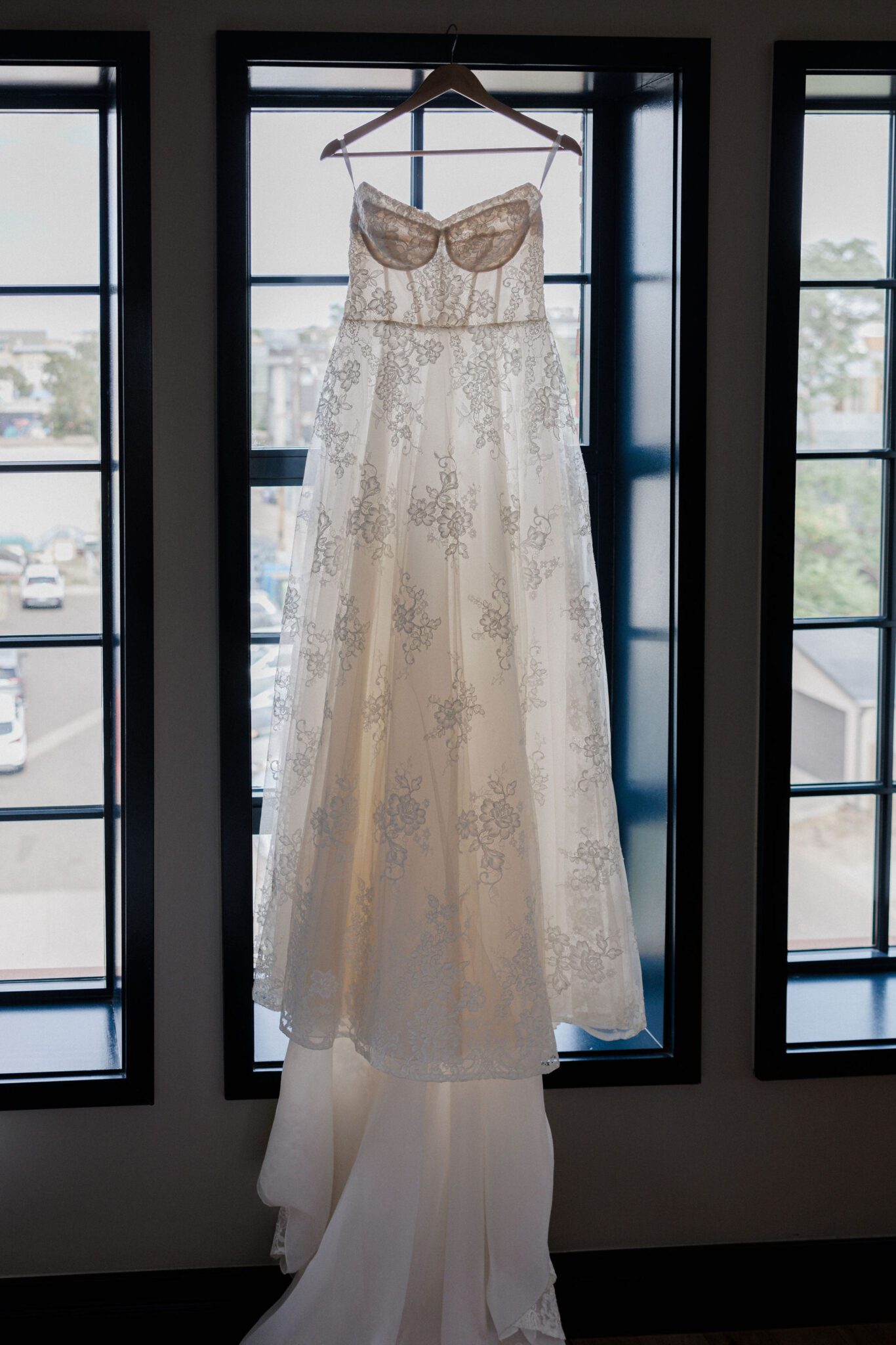 wedding dress hangs from window in the suite at the ramble hotel, a chic denver wedding venue