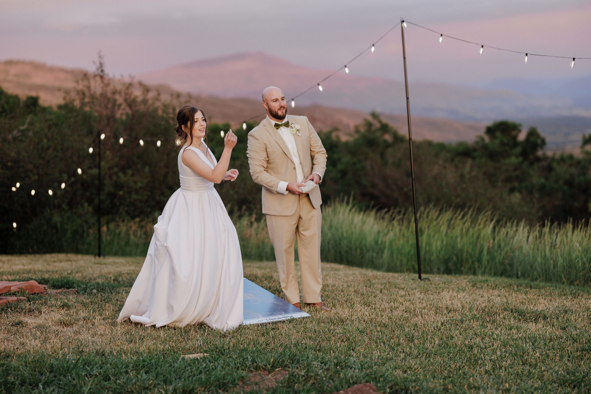 bride and groom play cornhole during summer wedding reception at a colorado airbnb